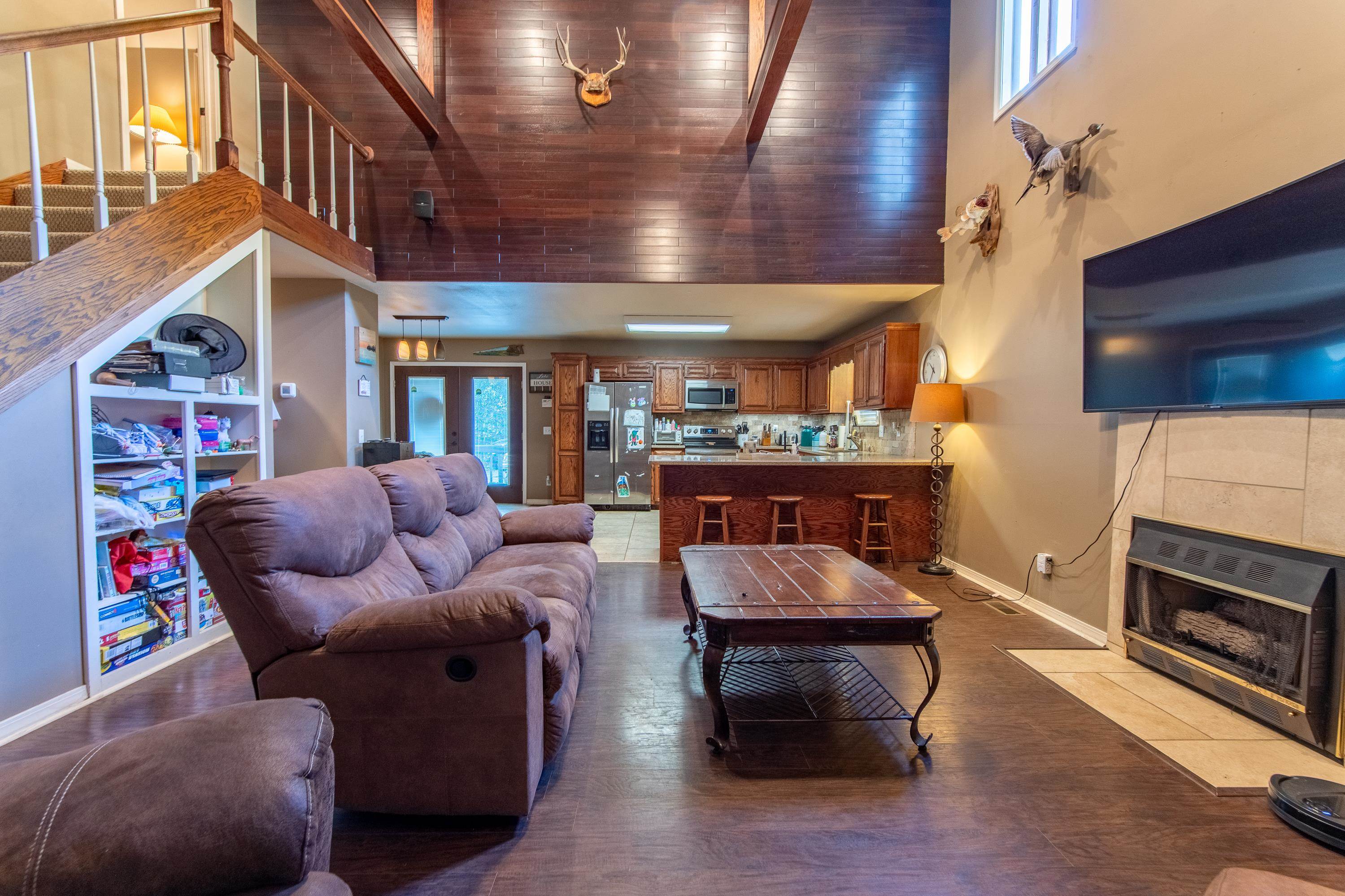 Living room with wood ceiling, a tile fireplace, hardwood / wood-style flooring, and a towering ceiling