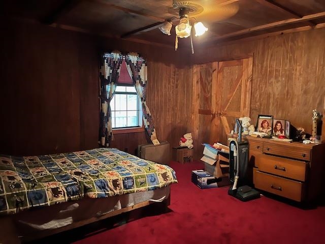 Bedroom featuring carpet, ceiling fan, and wood walls