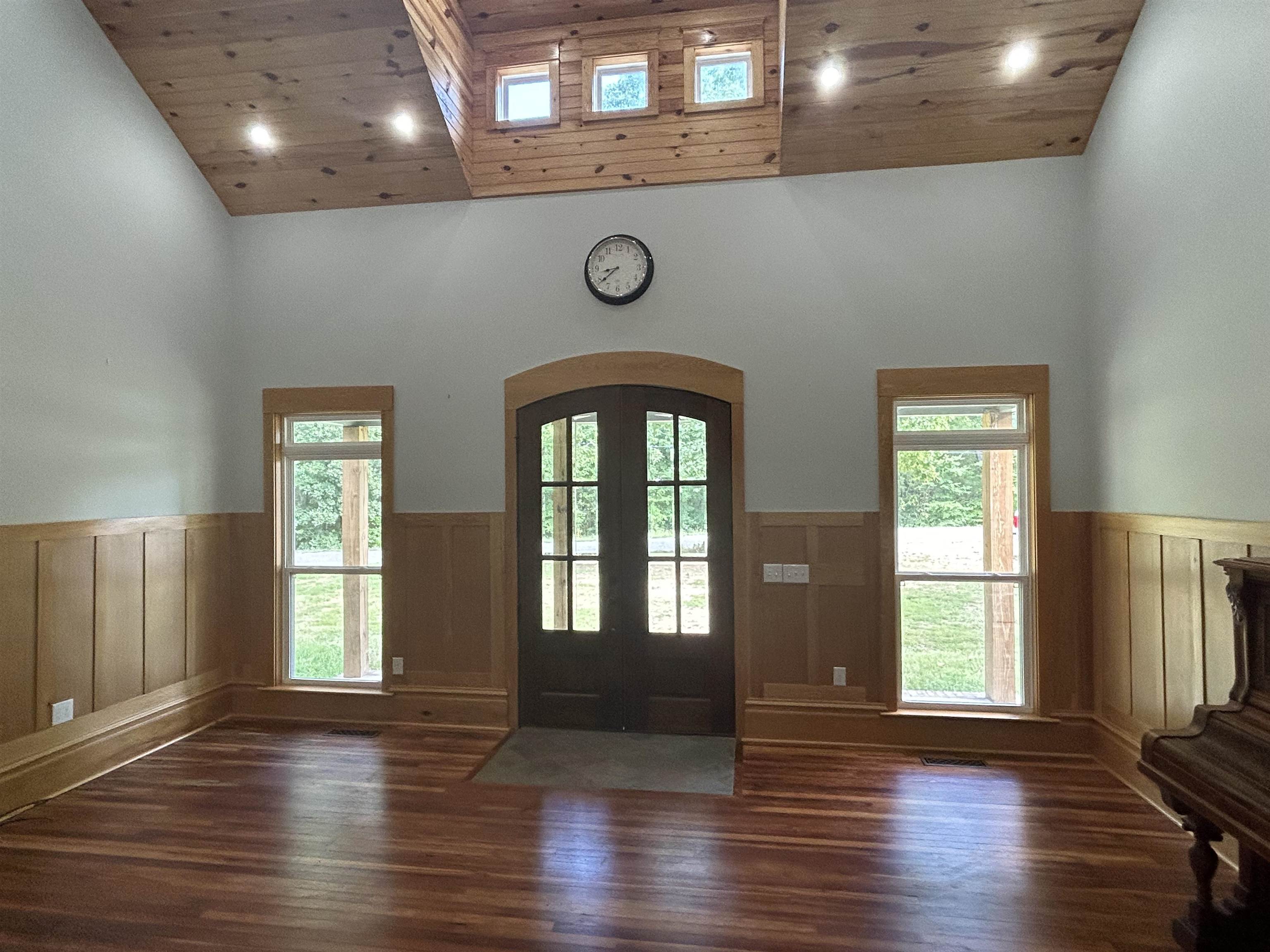 Foyer featuring dark wood-type flooring, high vaulted ceiling, and plenty of natural light