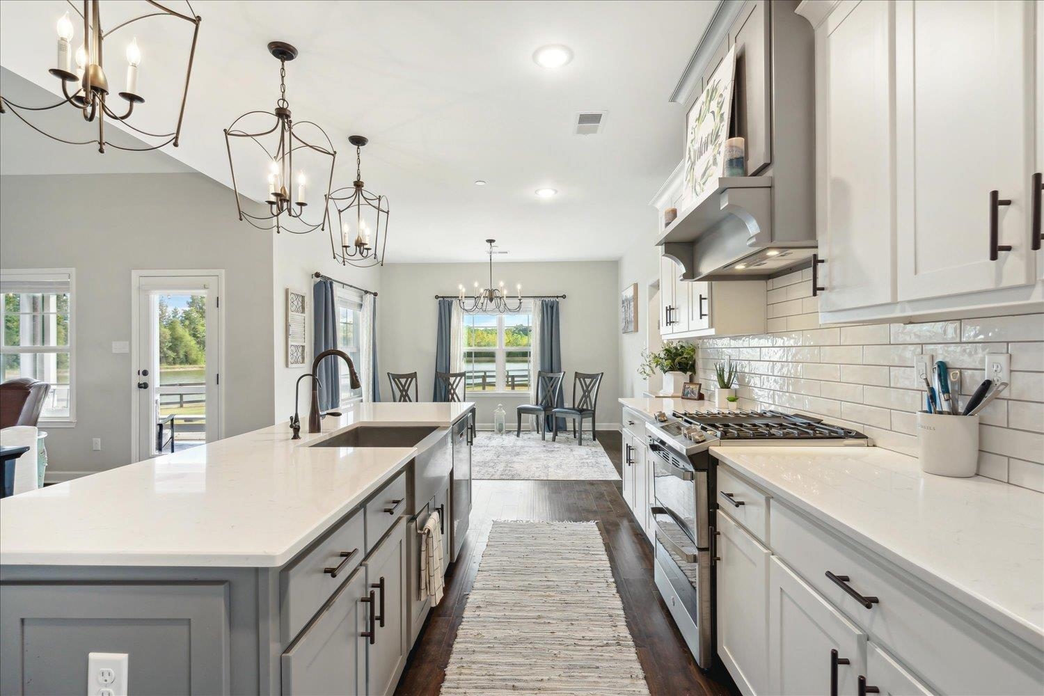 Kitchen with pendant lighting, dark hardwood / wood-style floors, stainless steel gas range, and a kitchen island with sink