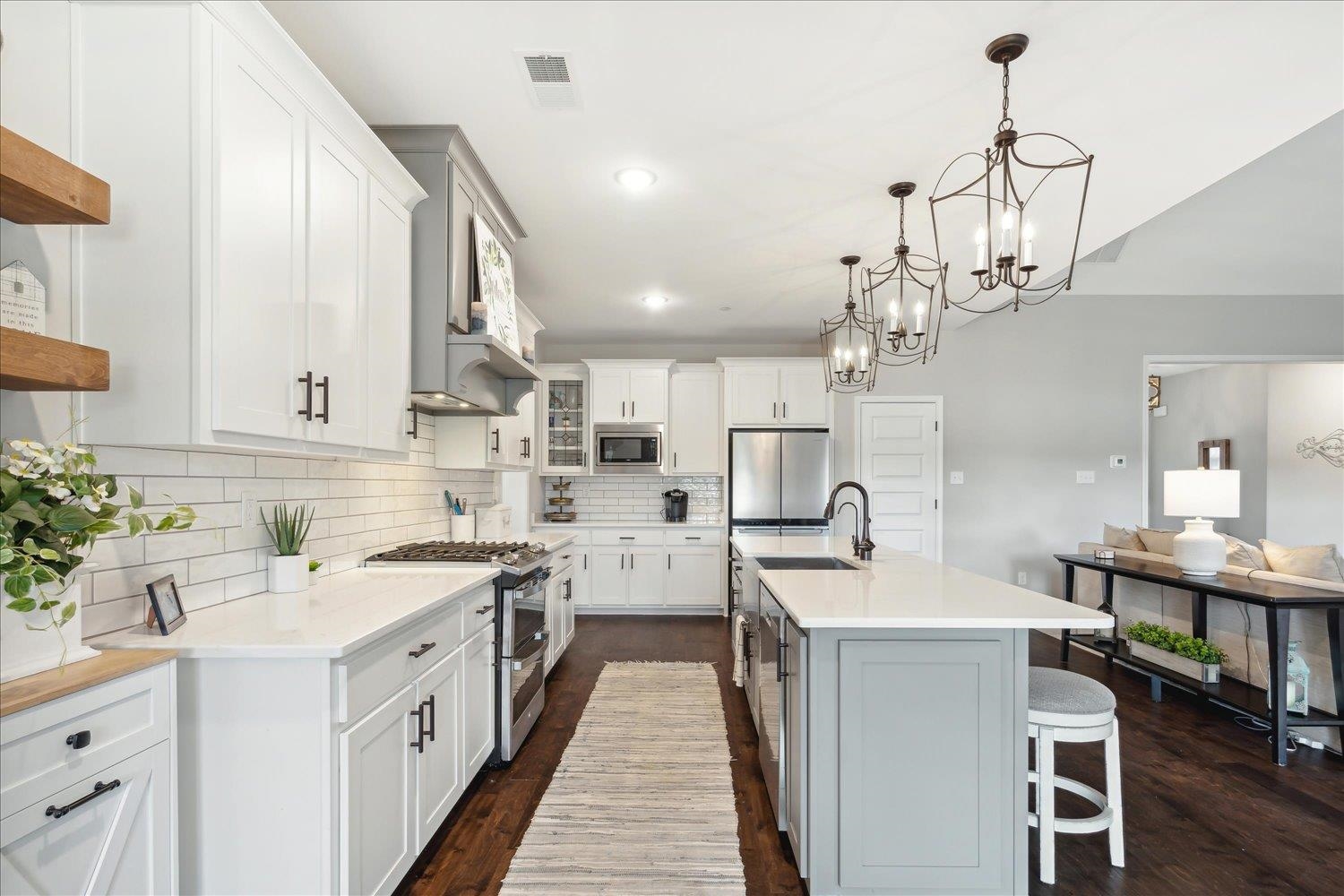 Kitchen with a kitchen island with sink, pendant lighting, white cabinetry, appliances with stainless steel finishes, and a breakfast bar area