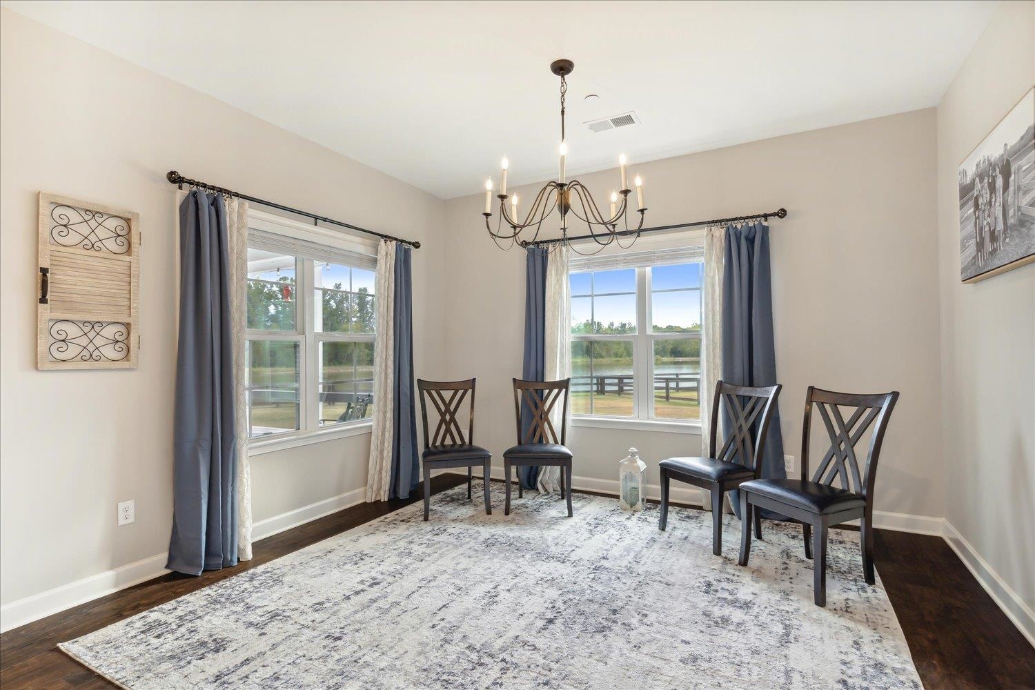 Sitting room with dark wood-type flooring, a healthy amount of sunlight, and a notable chandelier