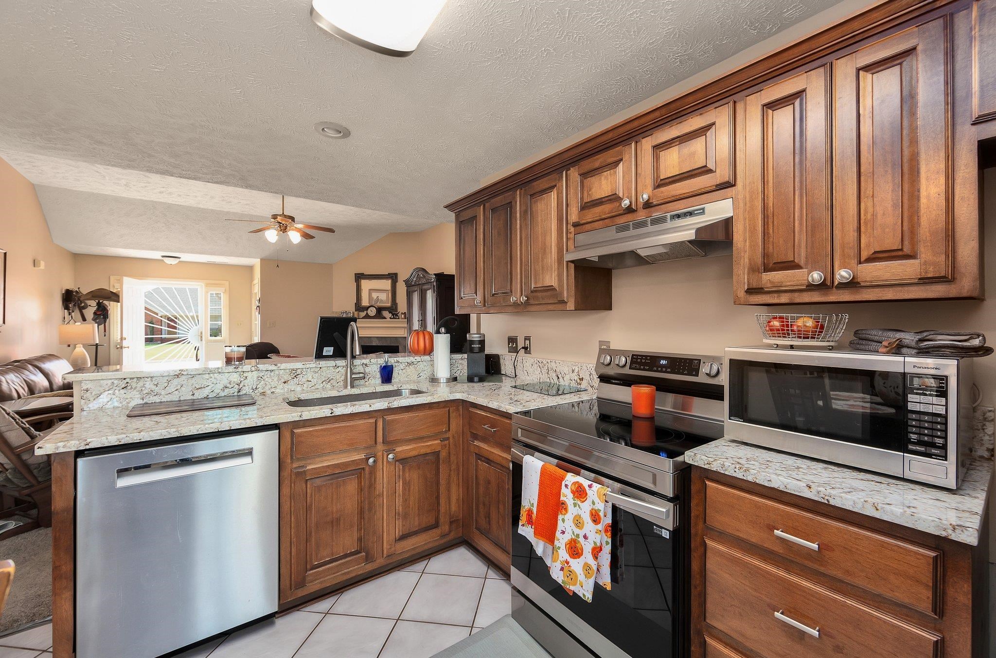 Kitchen with ceiling fan, kitchen peninsula, stainless steel appliances, and sink