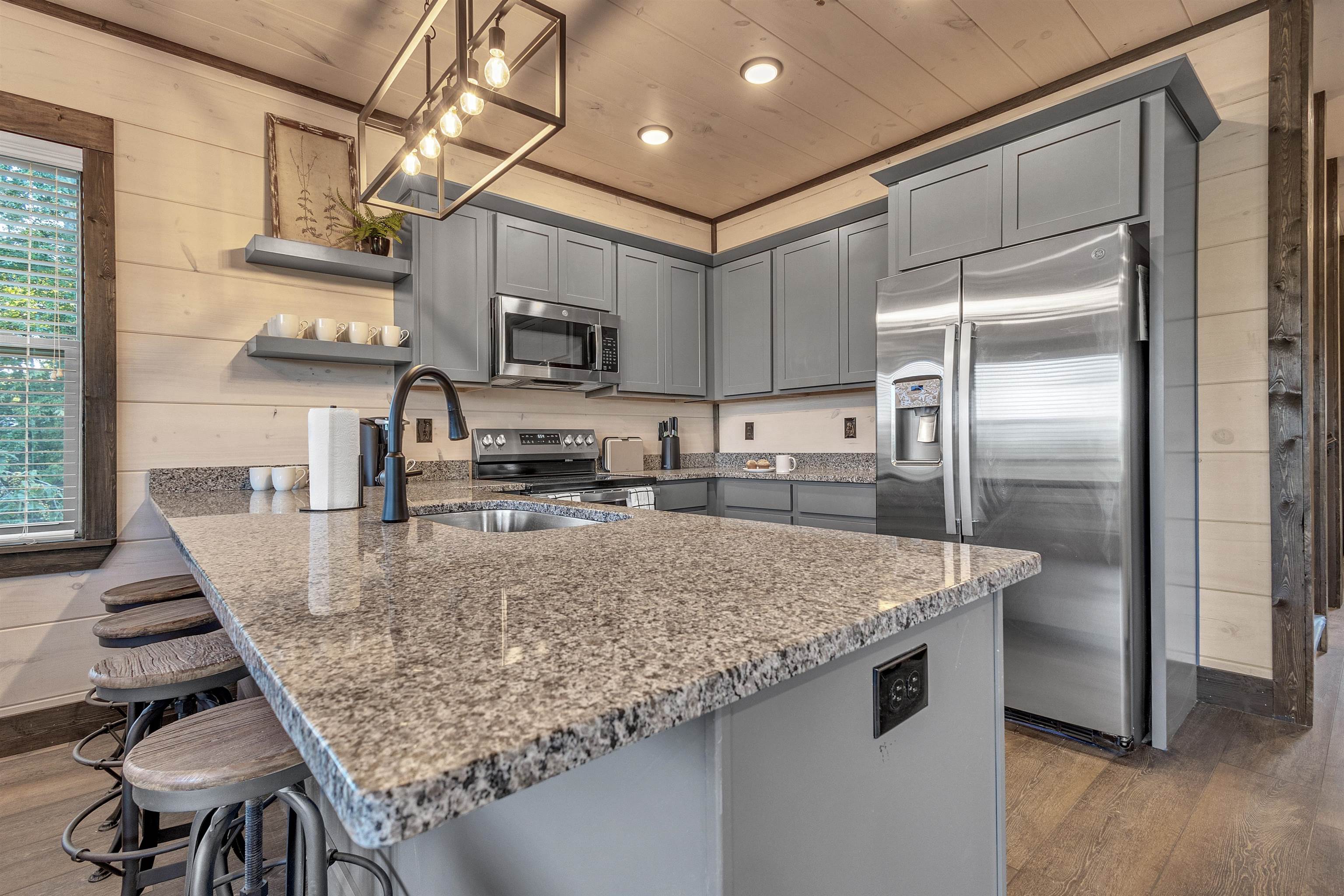 Kitchen featuring appliances with stainless steel finishes, wooden walls, wood-type flooring, and a healthy amount of sunlight