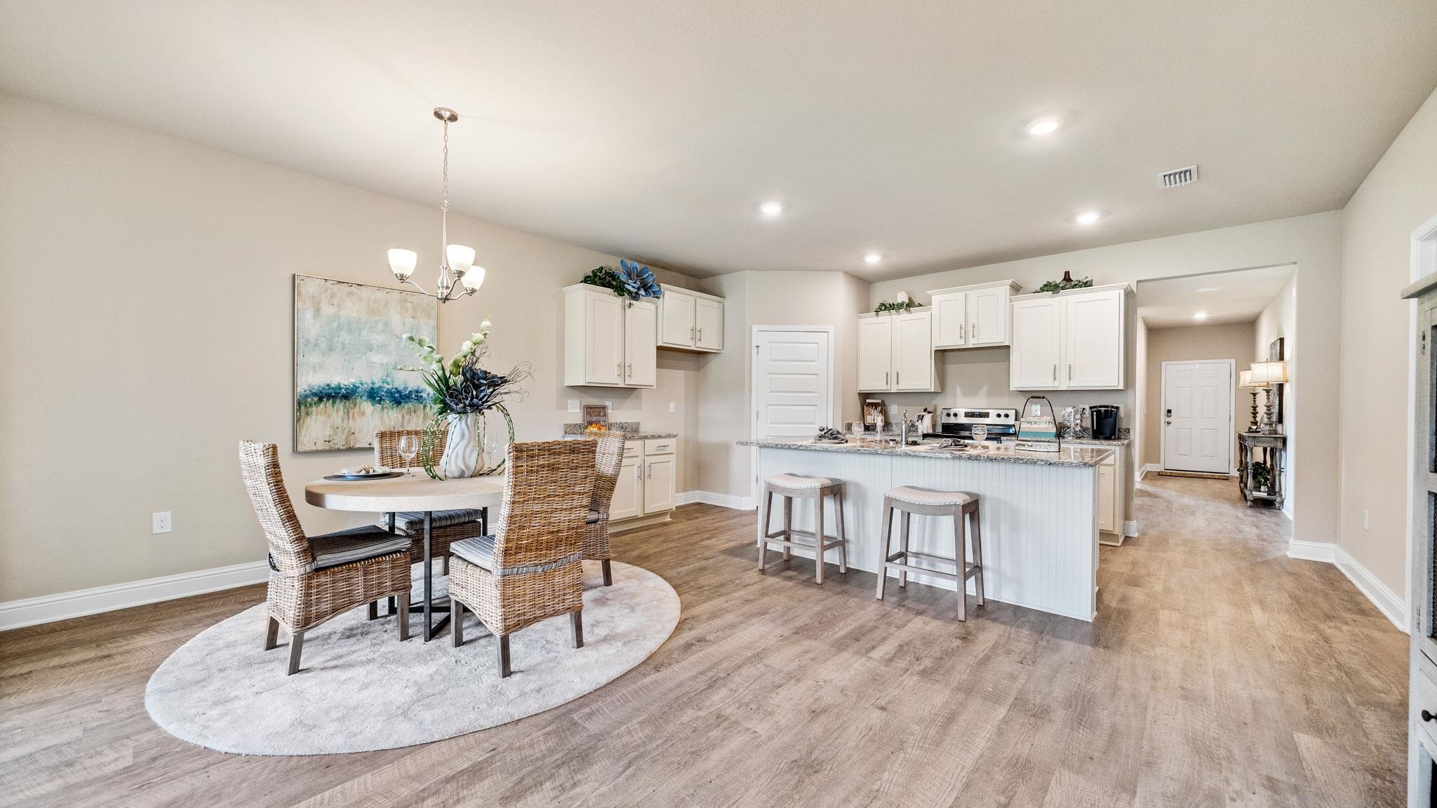 Interior space with a kitchen breakfast bar, a center island with sink, stove, light wood-type flooring, and white cabinets