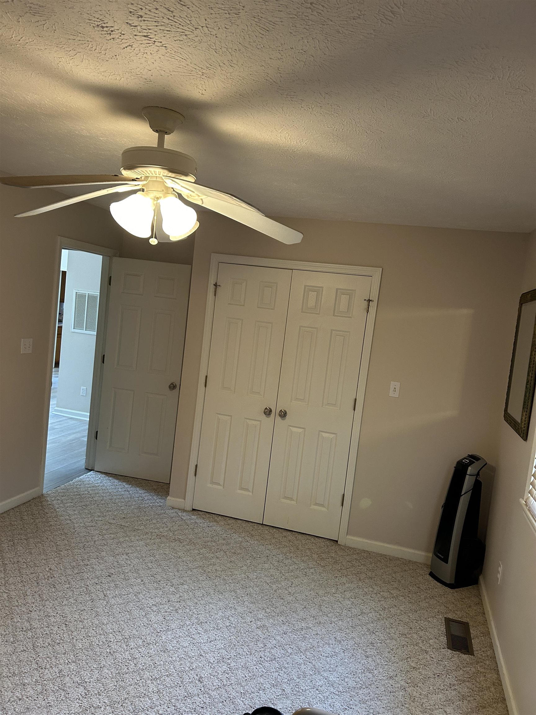 Interior space featuring a closet, ceiling fan, light carpet, and a textured ceiling