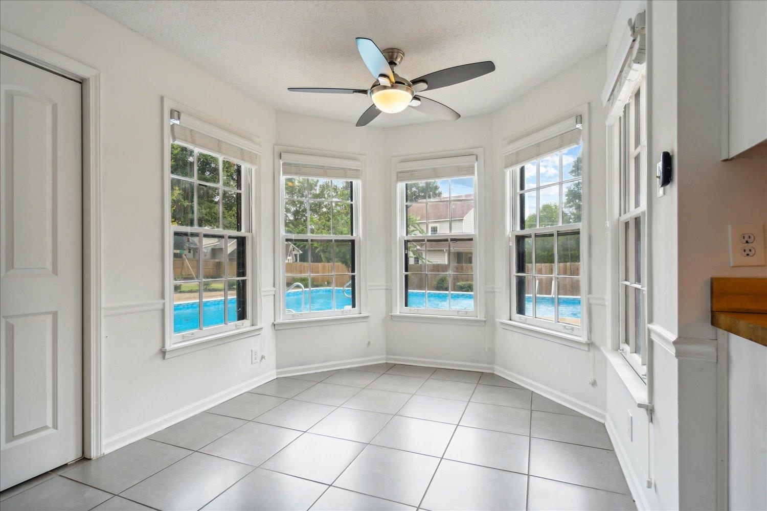 Unfurnished sunroom featuring ceiling fan