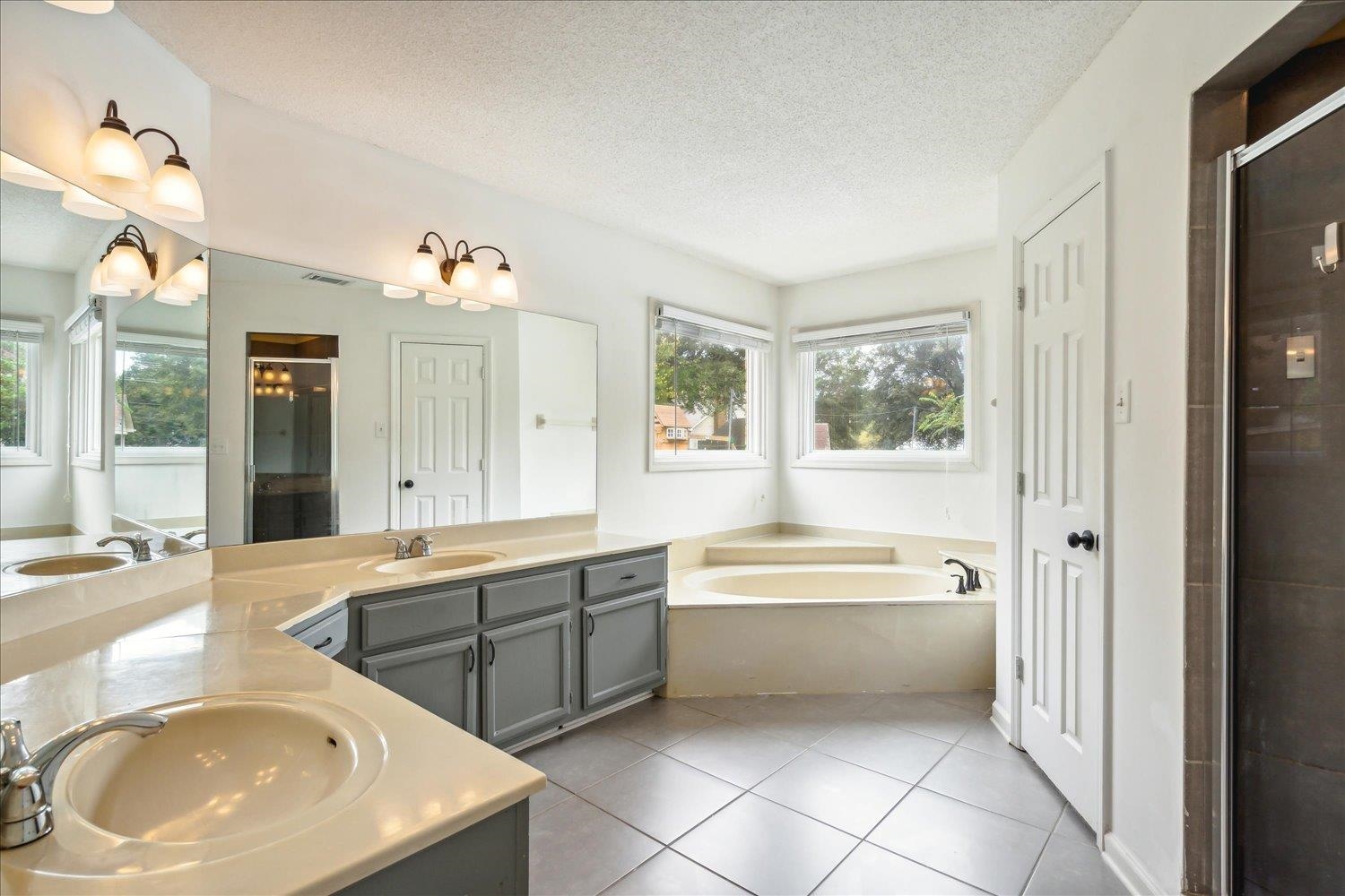 Bathroom with a textured ceiling, vanity, tile patterned floors, and shower with separate bathtub