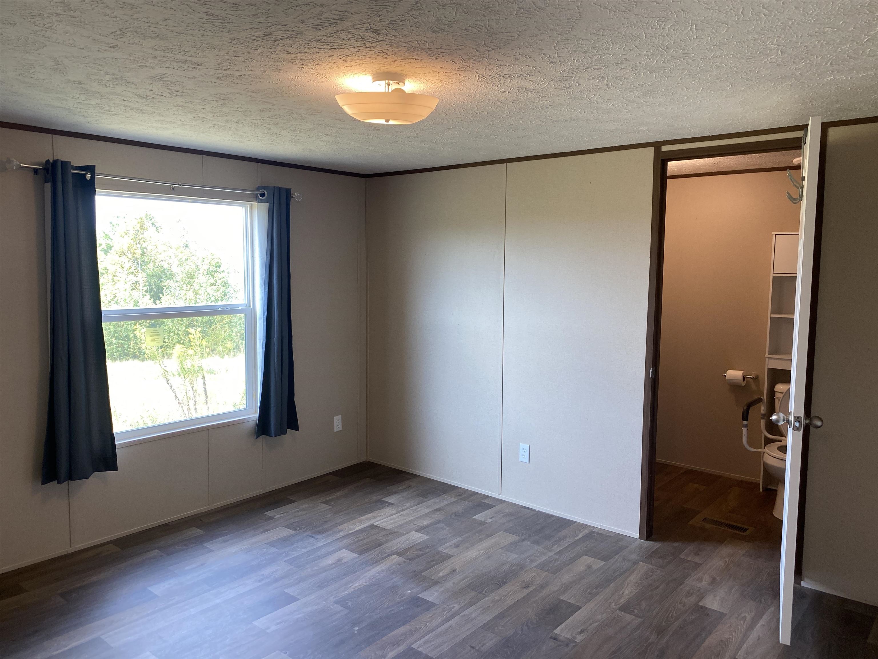 Unfurnished bedroom with dark hardwood / wood-style flooring and a textured ceiling