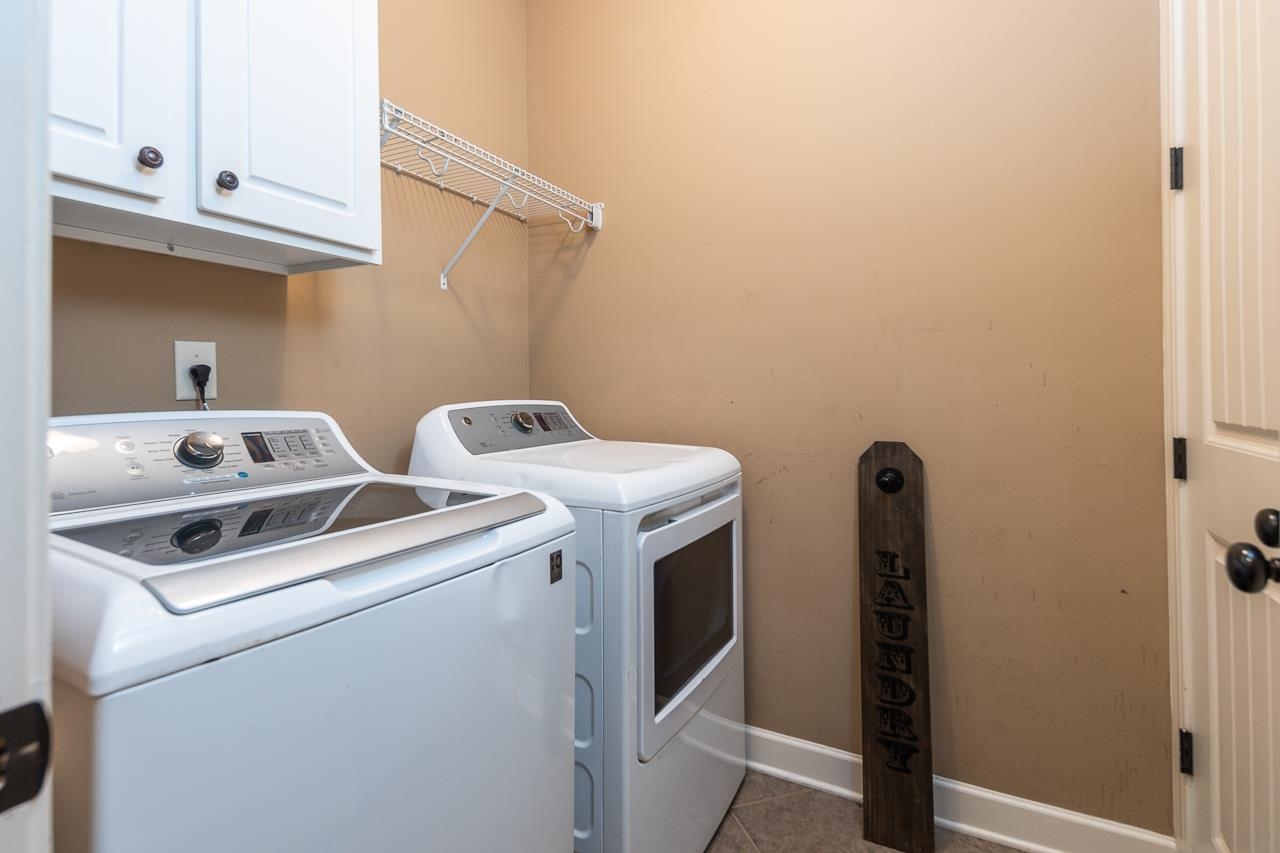 Washroom with washing machine and clothes dryer, cabinets, and tile patterned floors