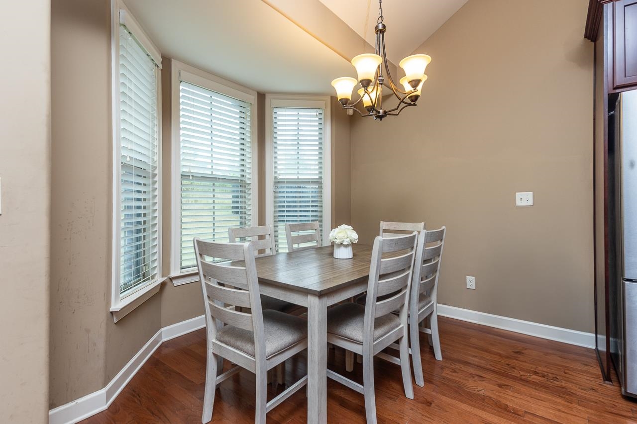 Dining area with vaulted ceiling, dark wood-type flooring, and a notable chandelier