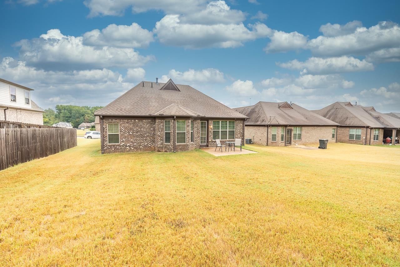 Rear view of property featuring a lawn and a patio area