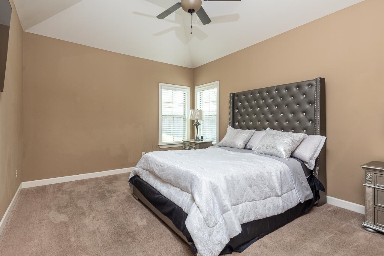 Carpeted bedroom featuring lofted ceiling and ceiling fan