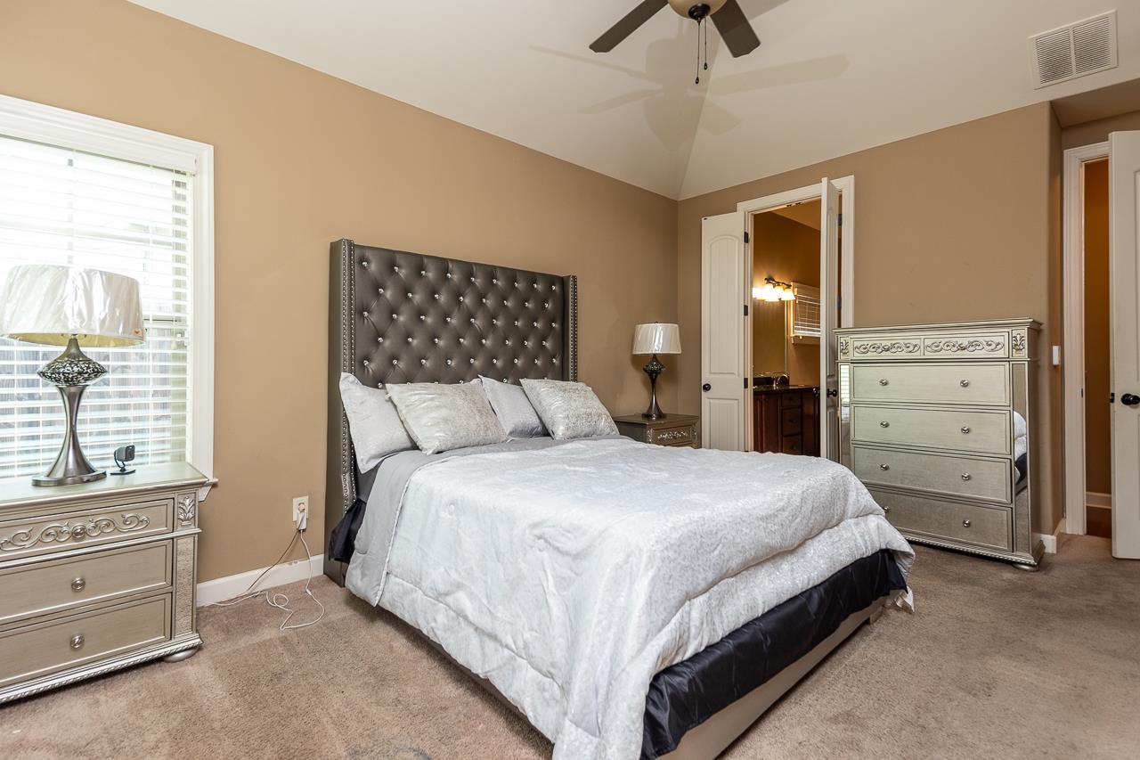 Bedroom with lofted ceiling, ceiling fan, and carpet