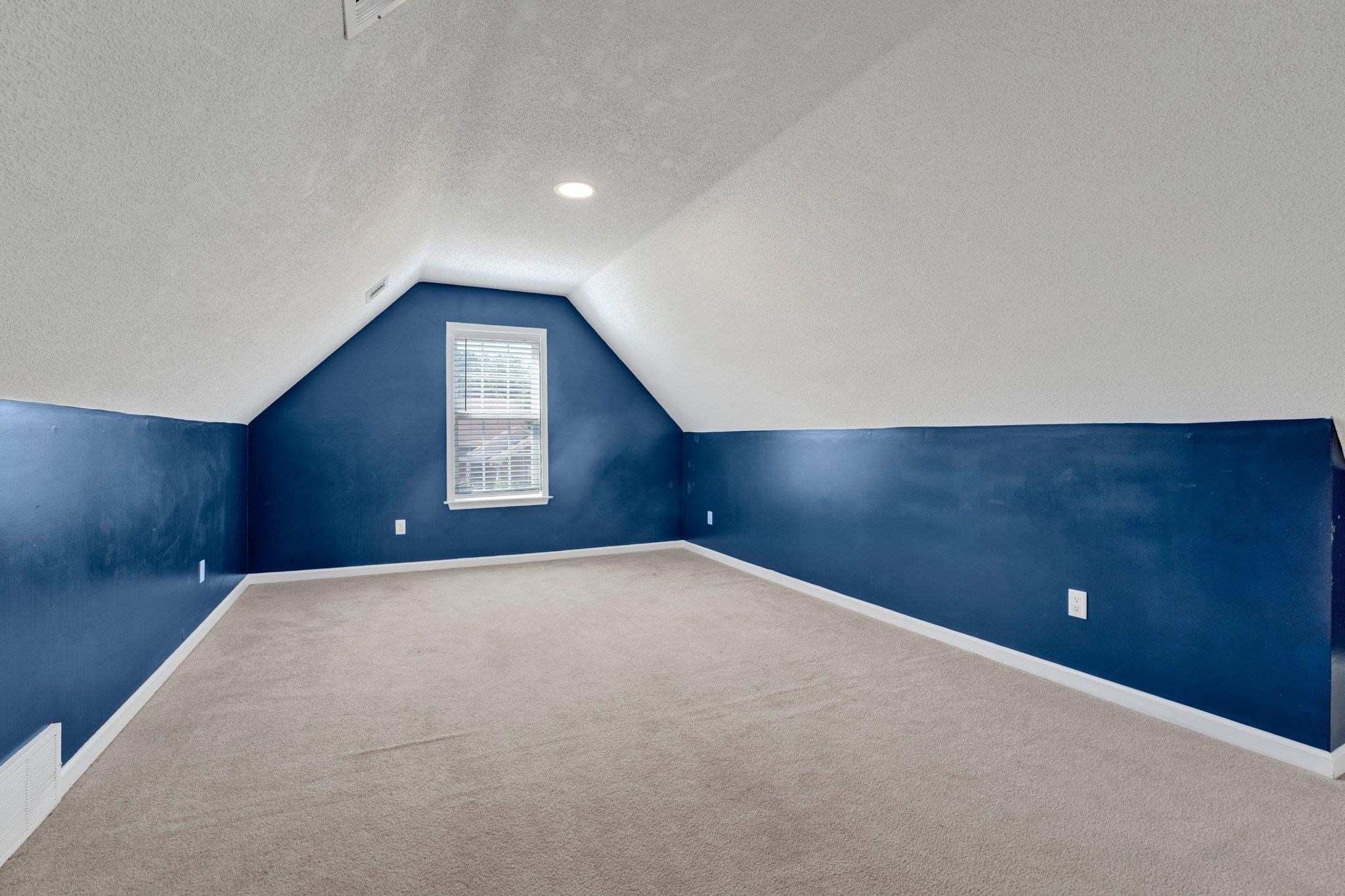 Additional living space featuring lofted ceiling, carpet flooring, and a textured ceiling