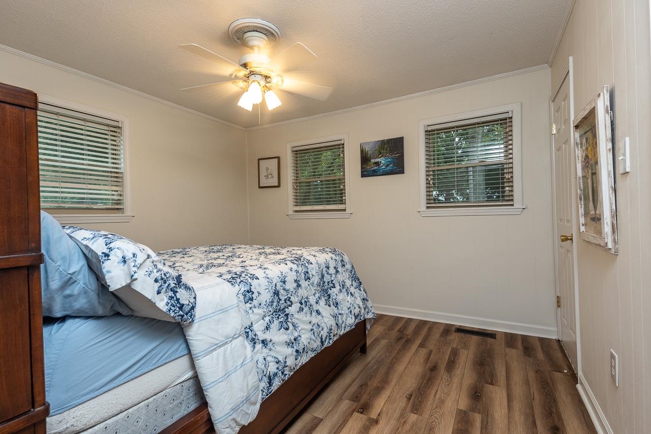 Bedroom featuring dark wood-type flooring, ceiling fan, crown molding, and a textured ceiling