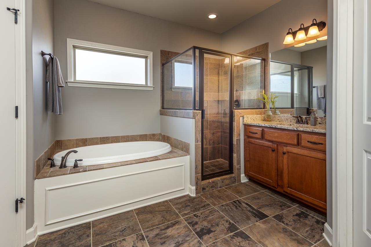 Bathroom featuring dual vanities , separate tiled shower and whirlpool tub