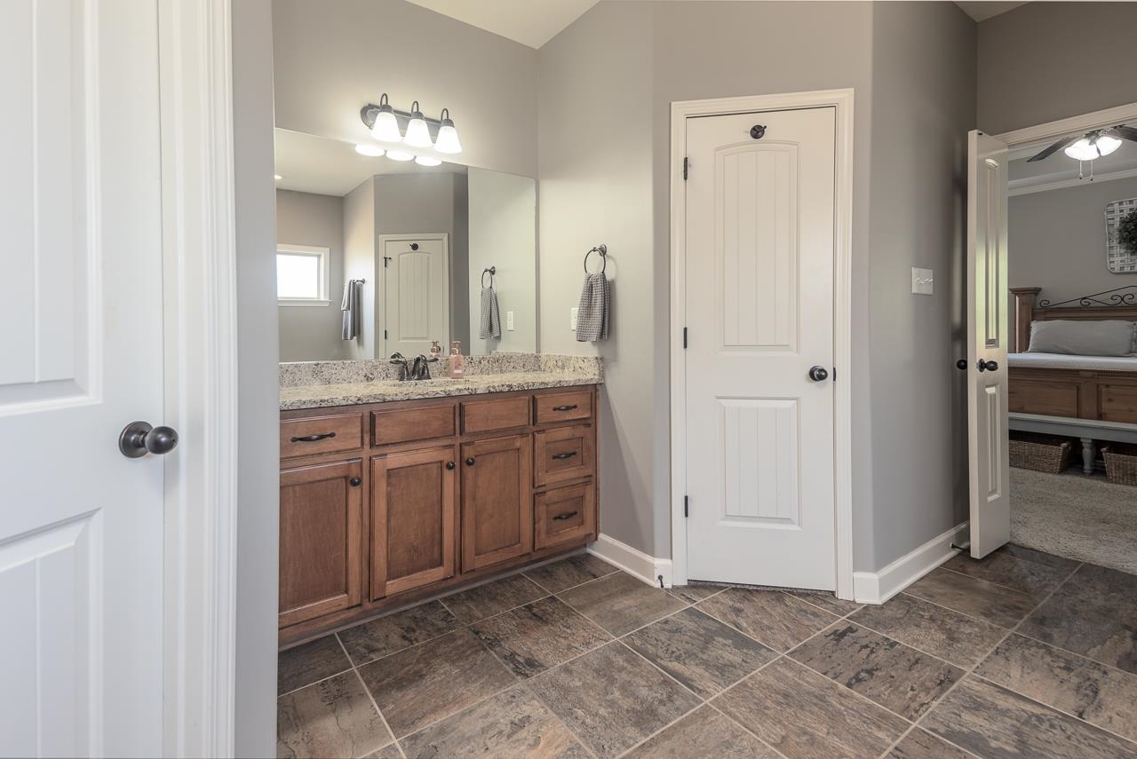 Bathroom featuring dual vanities, his/her closets and tile floor