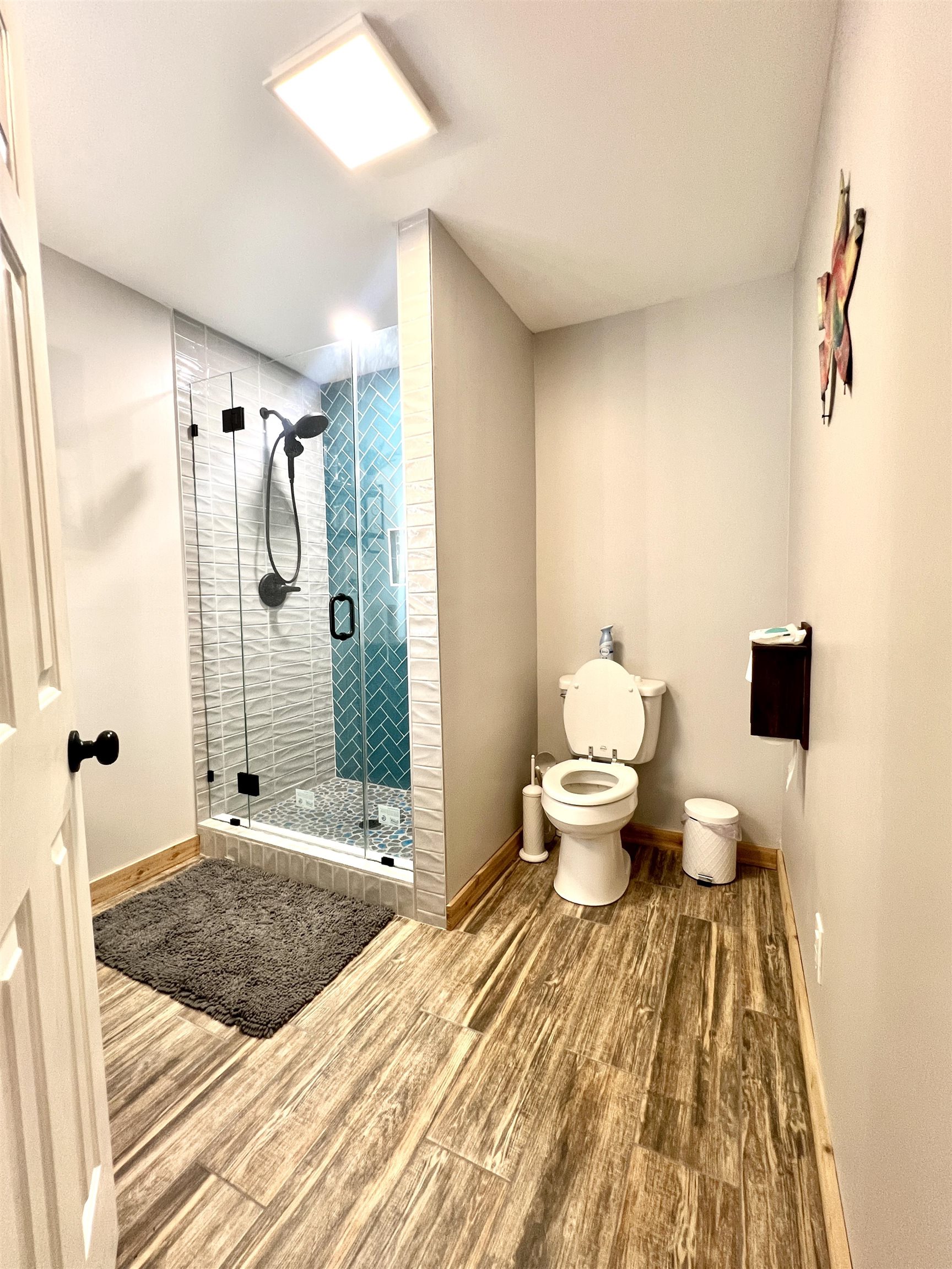 Downstairs full bathroom with tile floors, tile shower with door and single sink vanity.