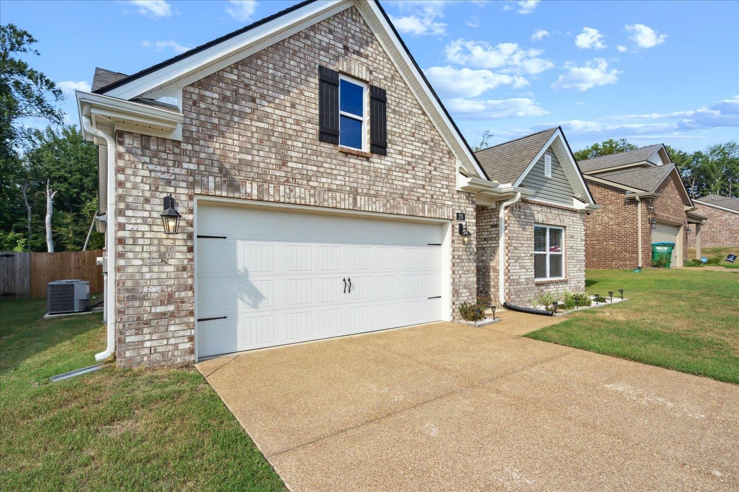 View of front of property featuring a front yard, central AC unit, and a garage