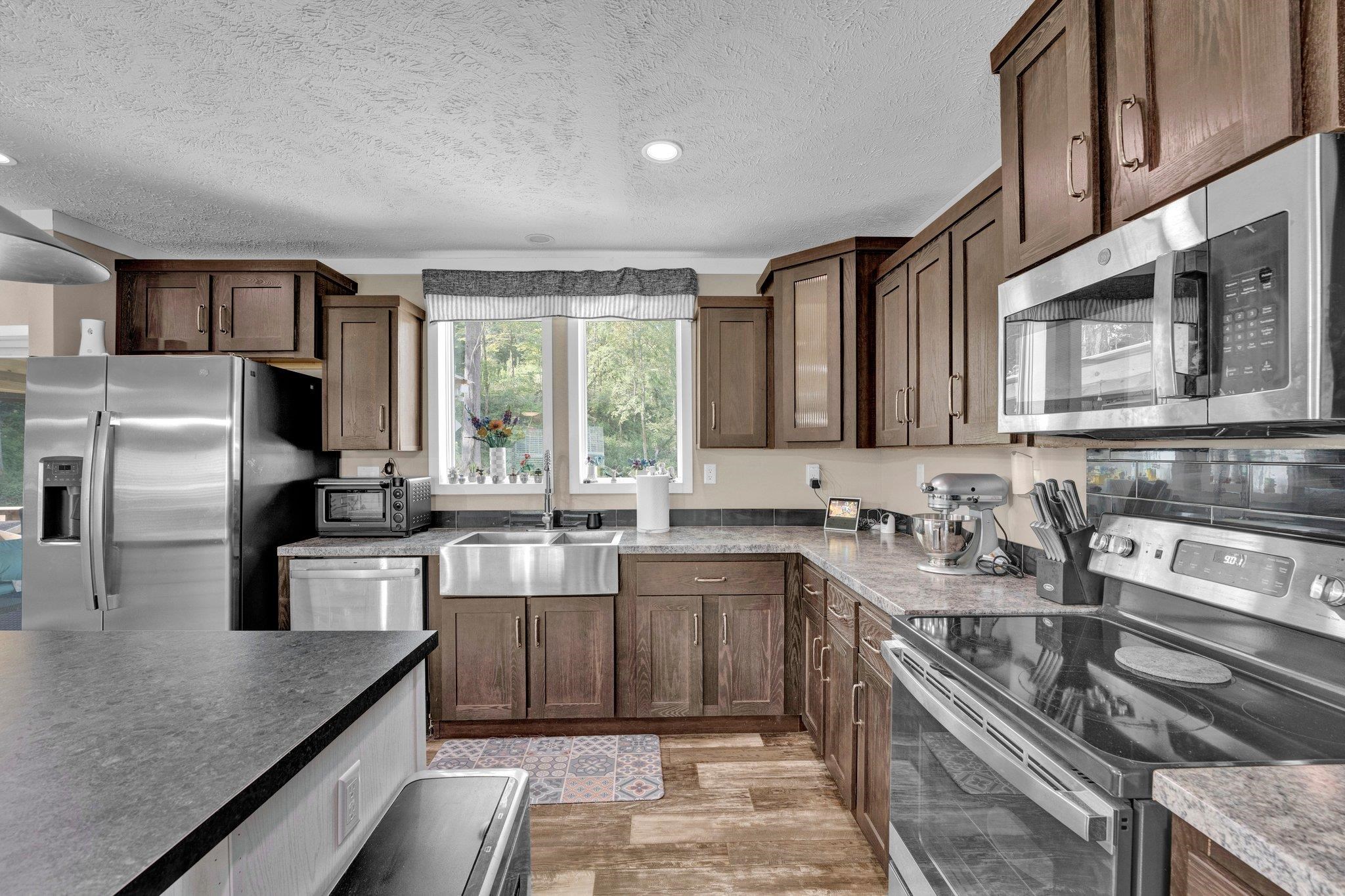 Kitchen featuring light wood-type flooring, appliances with stainless steel finishes, sink, and a textured ceiling