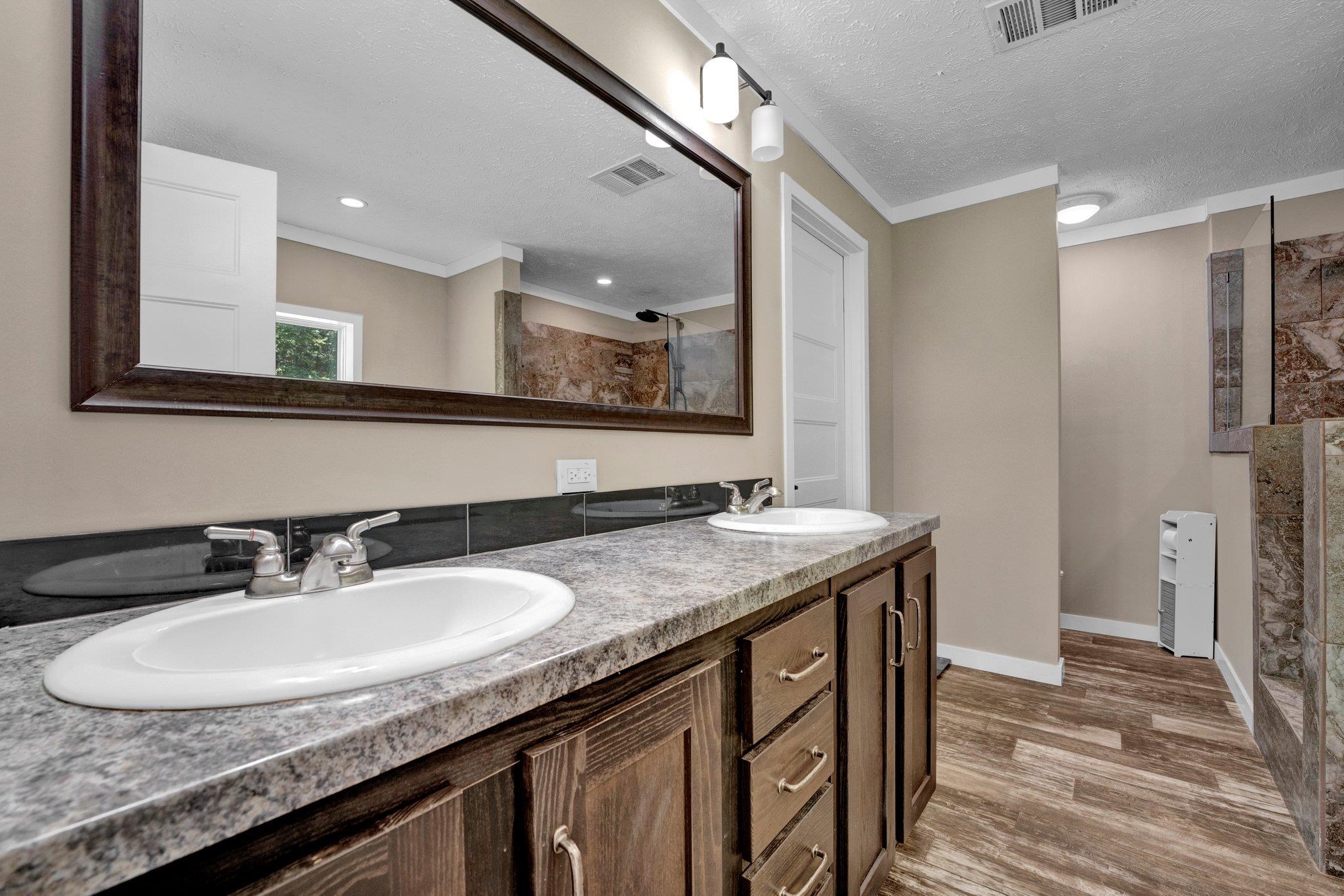 Bathroom featuring a textured ceiling, a shower, wood-type flooring, vanity, and ornamental molding