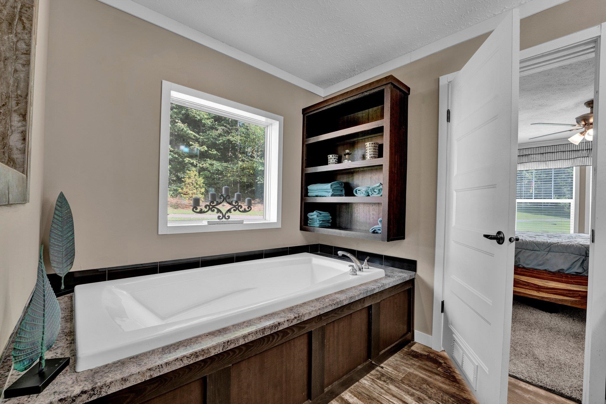 Bathroom featuring hardwood / wood-style floors, a bathing tub, crown molding, a textured ceiling, and ceiling fan