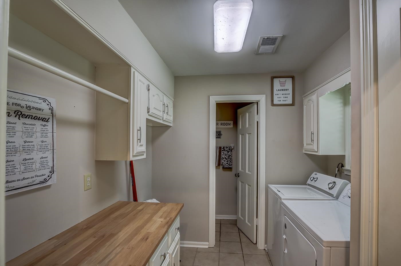 Laundry room with light tile patterned floors, cabinets, and washing machine and clothes dryer