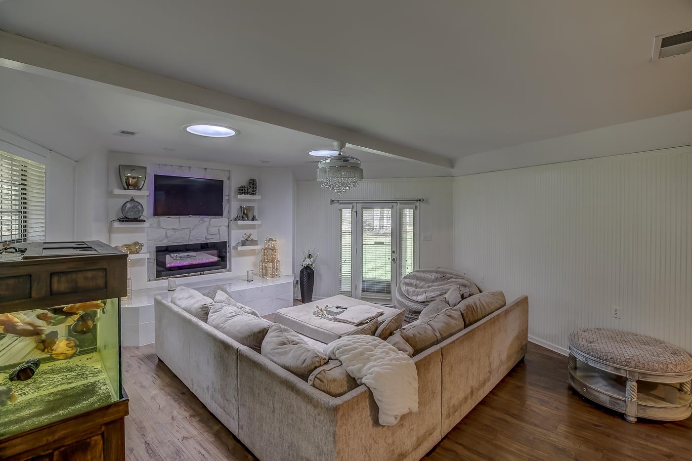 Living room with hardwood / wood-style floors, ceiling fan, a fireplace, and beamed ceiling