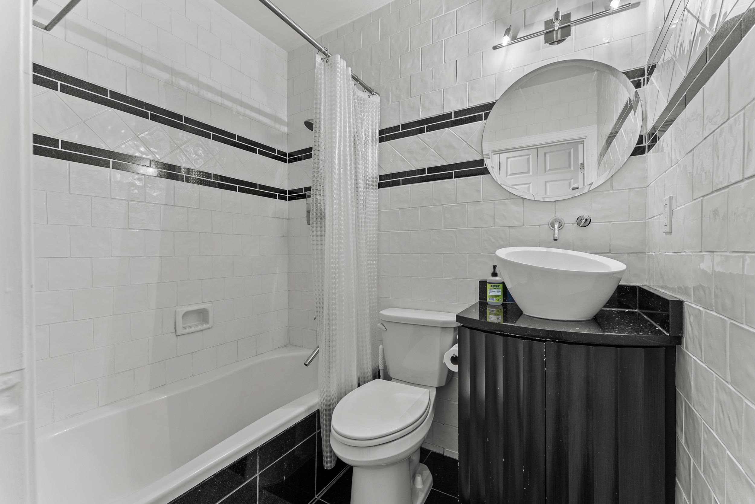 Full bathroom with vanity, toilet, tile walls, and shower / bath combo