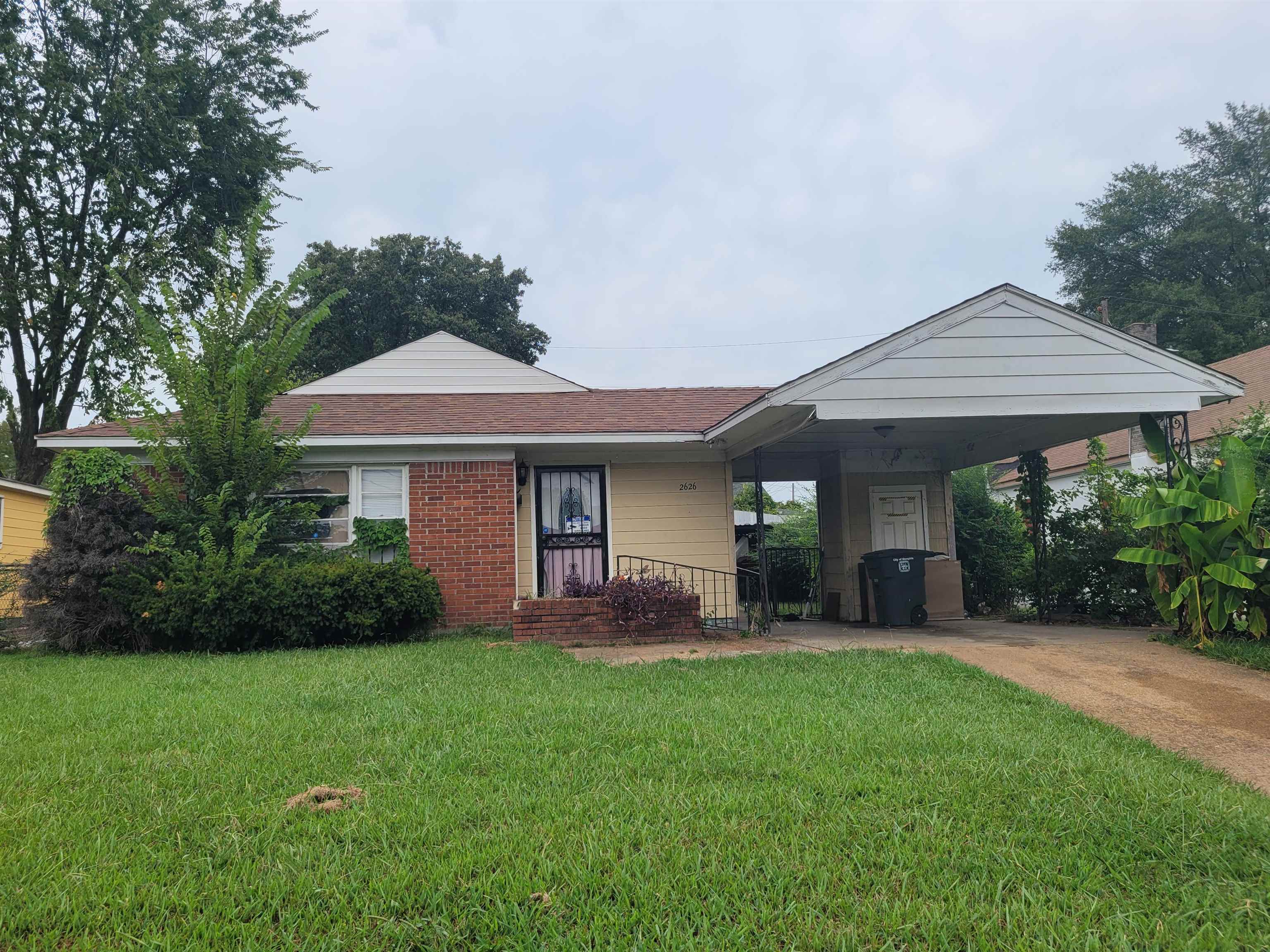 Single story home with a front lawn and a carport