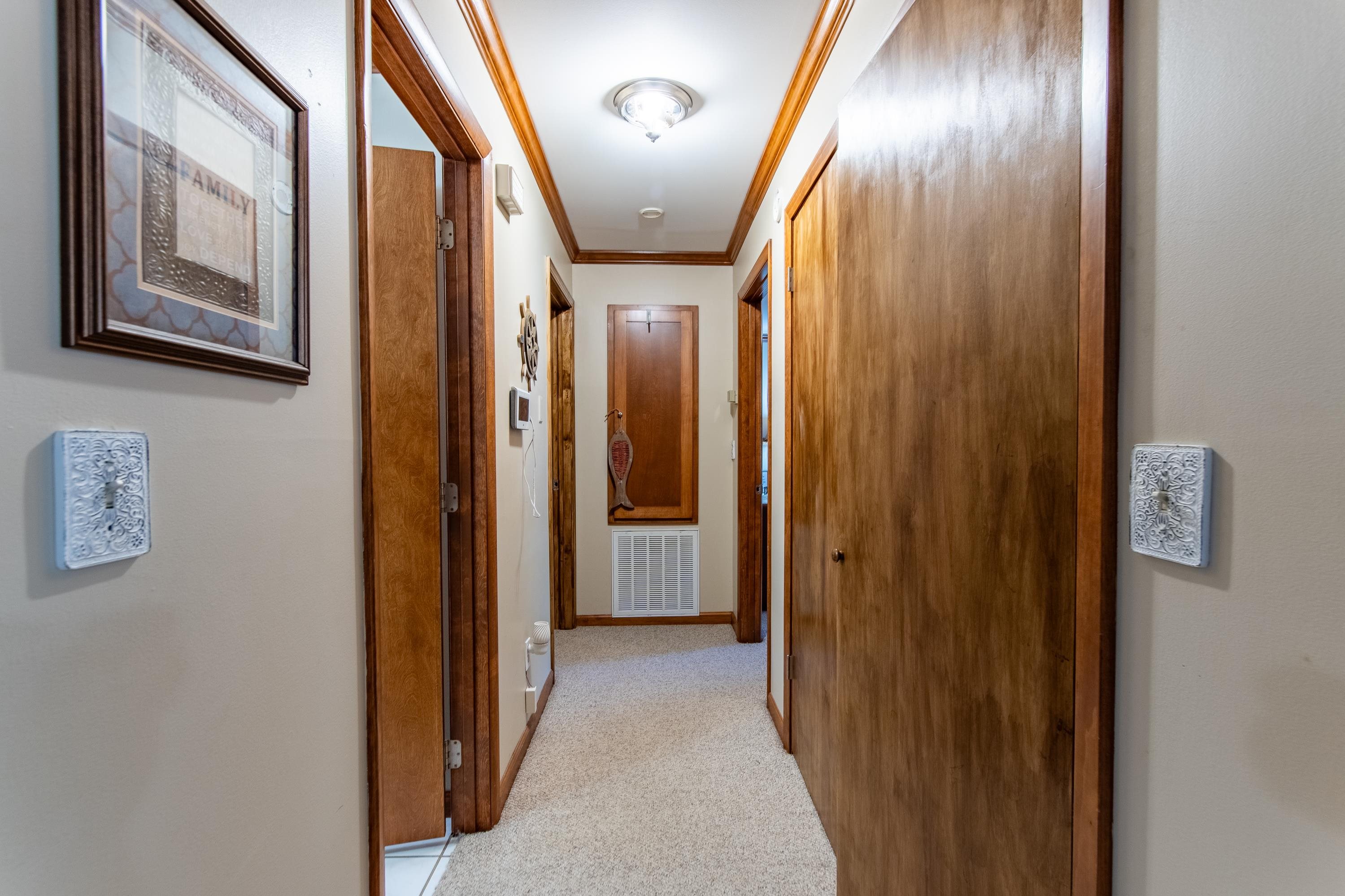 Hall with light colored carpet and ornamental molding