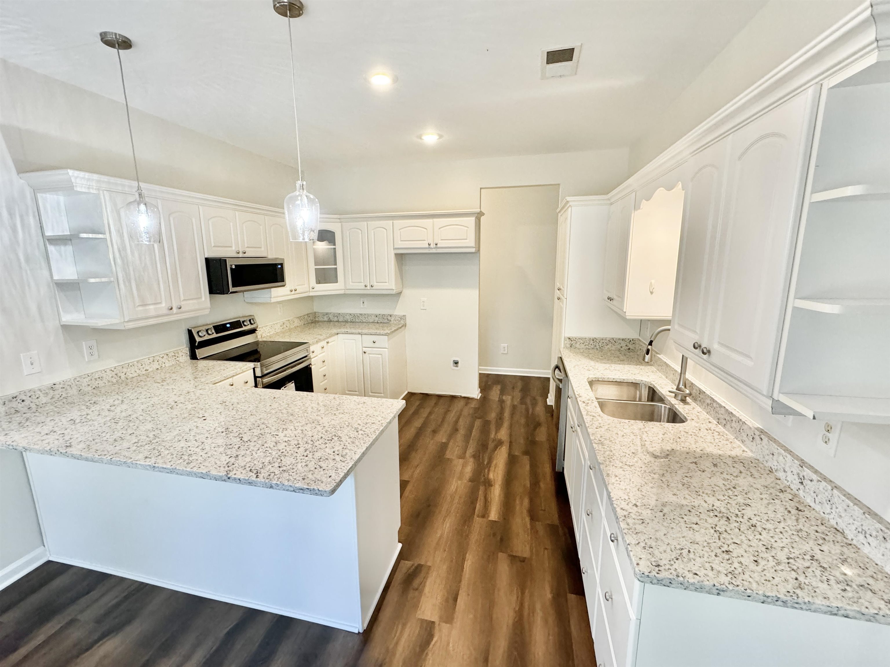 Kitchen featuring white cabinets, light stone countertops, stainless steel appliances, sink, and dark hardwood / wood-style floors