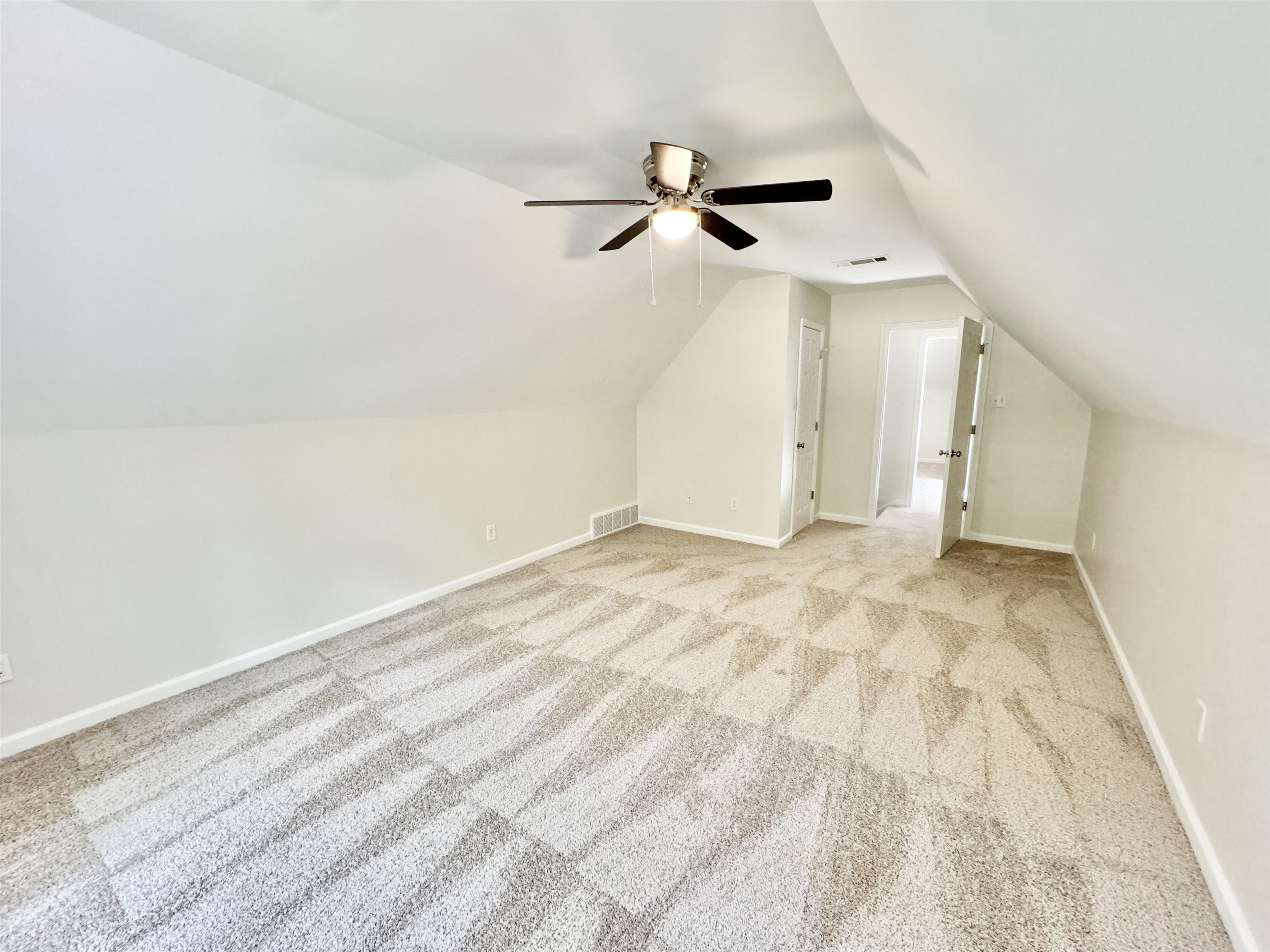 Additional living space with vaulted ceiling, light colored carpet, and ceiling fan