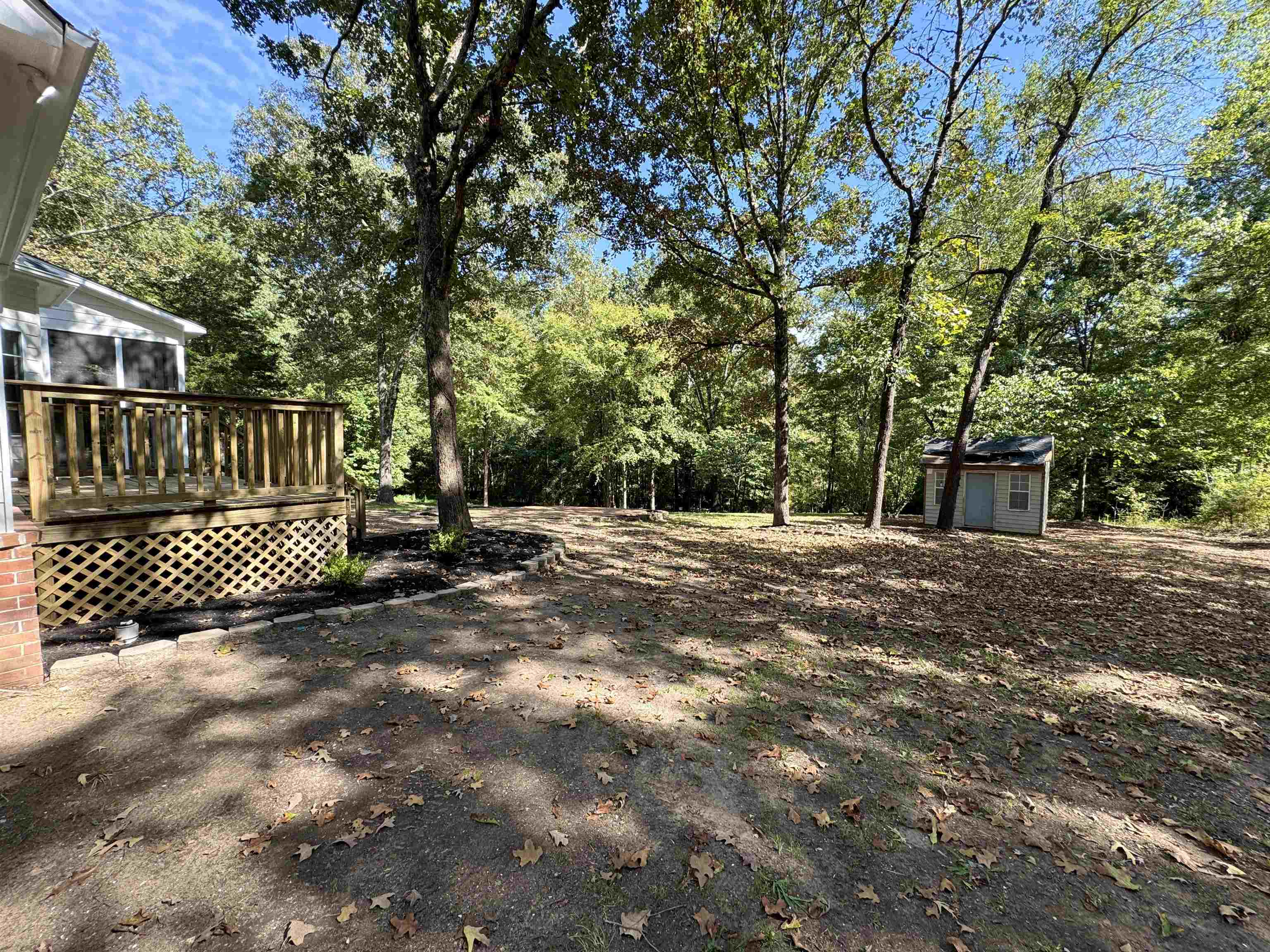 View of yard featuring a storage shed, a sunroom, and a wooden deck