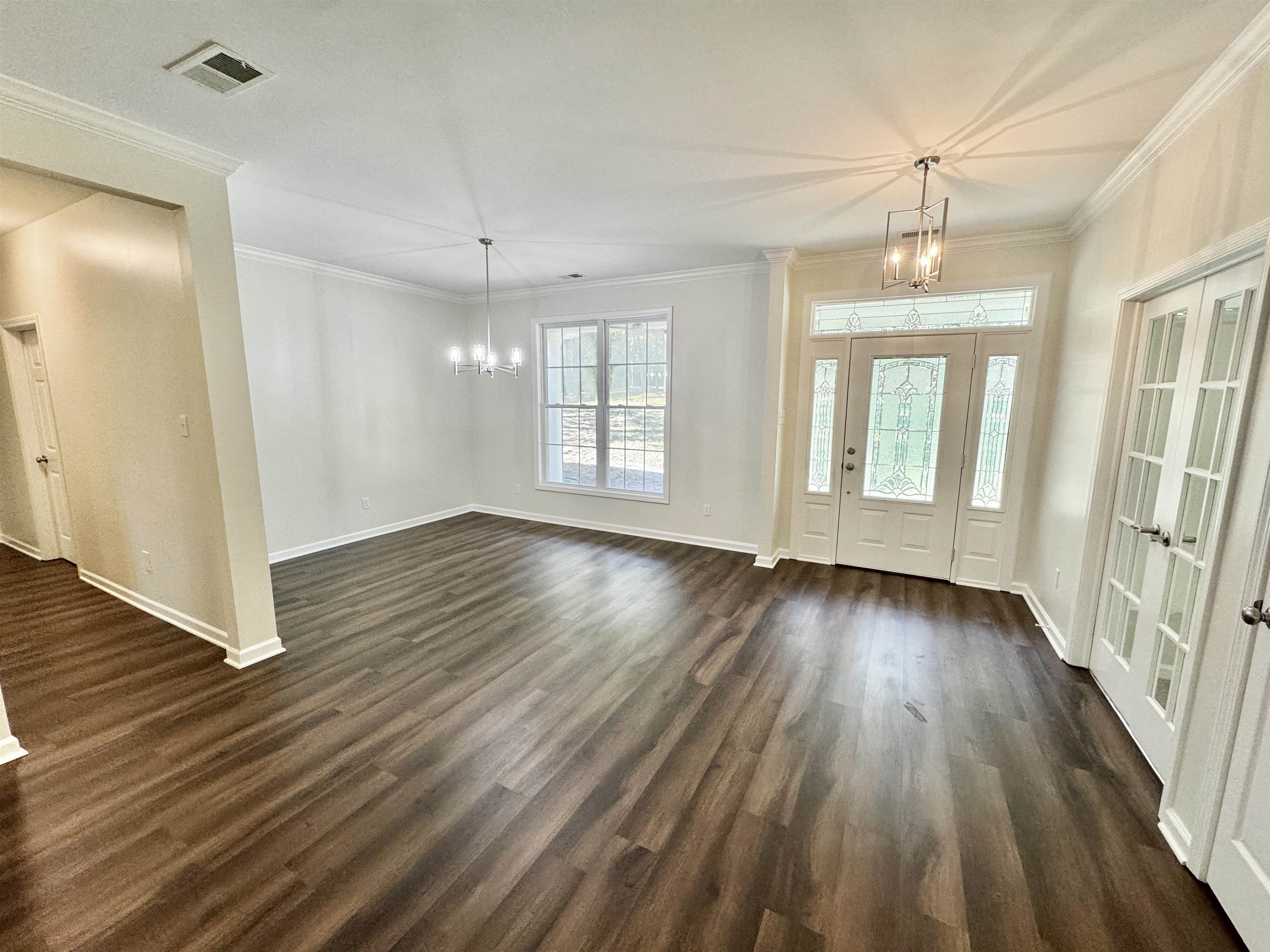 Interior space featuring ornamental molding, an inviting chandelier, dark hardwood / wood-style floors, and french doors