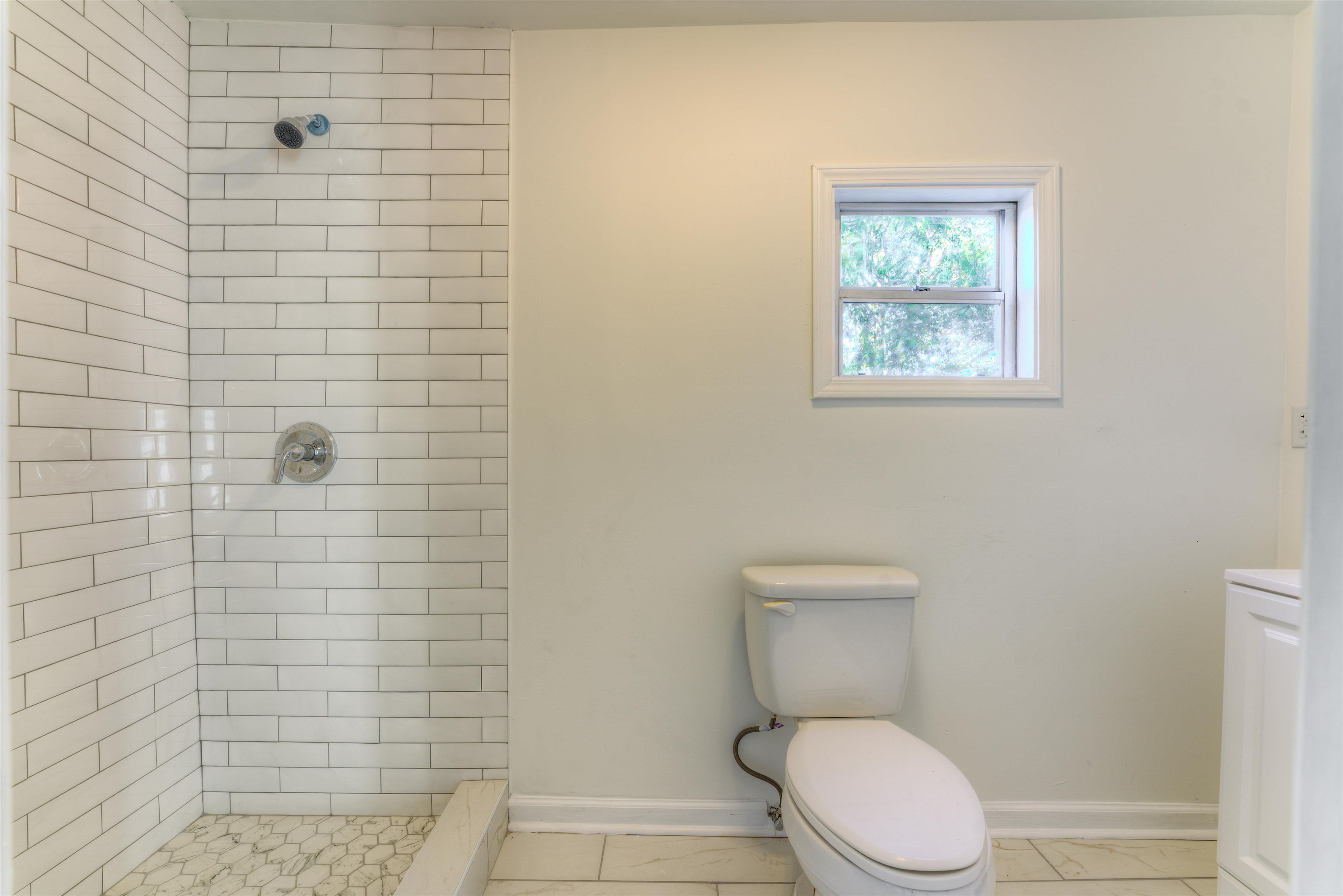 Bathroom with tiled shower, toilet, and tile patterned floors