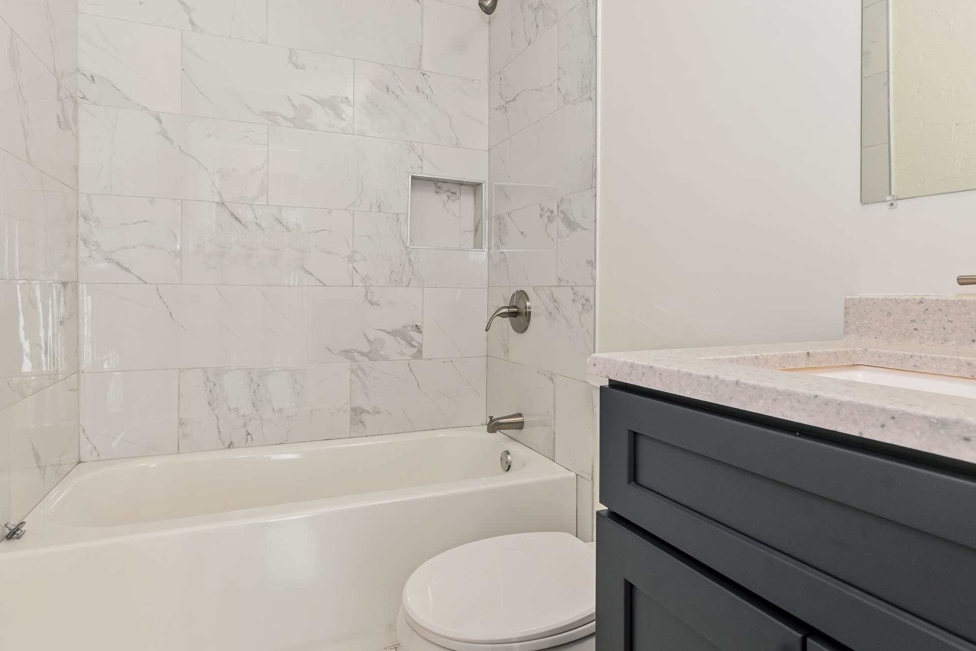 Full bathroom with toilet, tiled shower / bath combo, and vanity