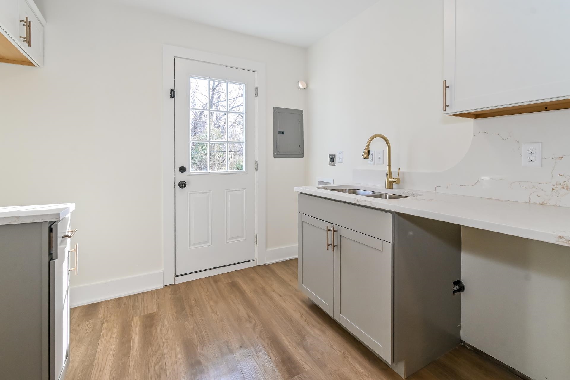 Laundry room featuring light hardwood / wood-style flooring, sink, and electric panel