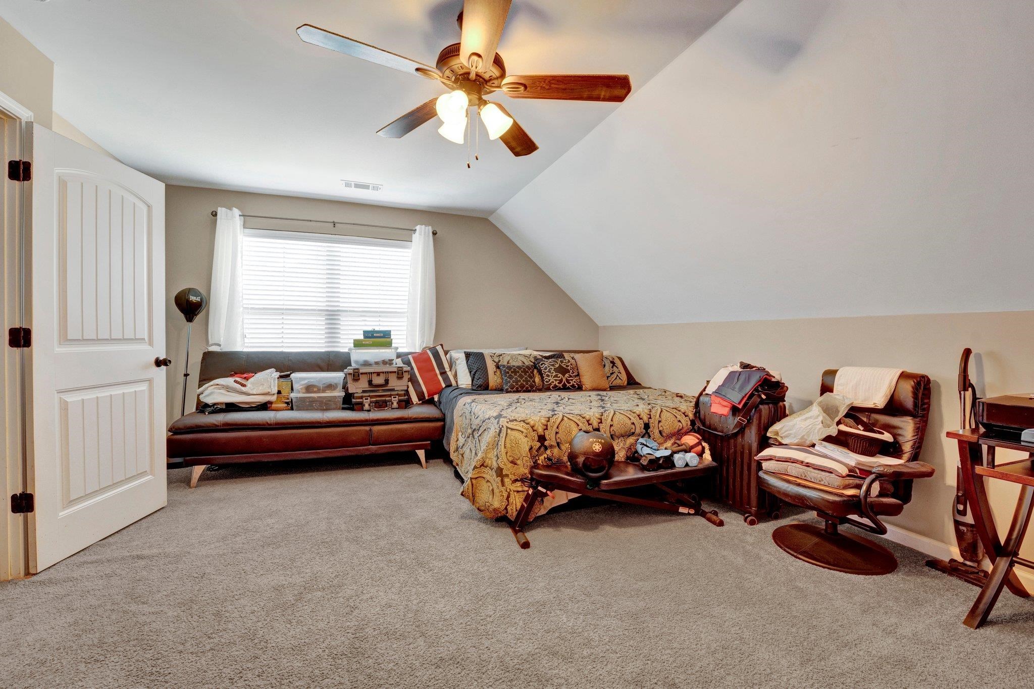 Bedroom featuring lofted ceiling, ceiling fan, and light carpet