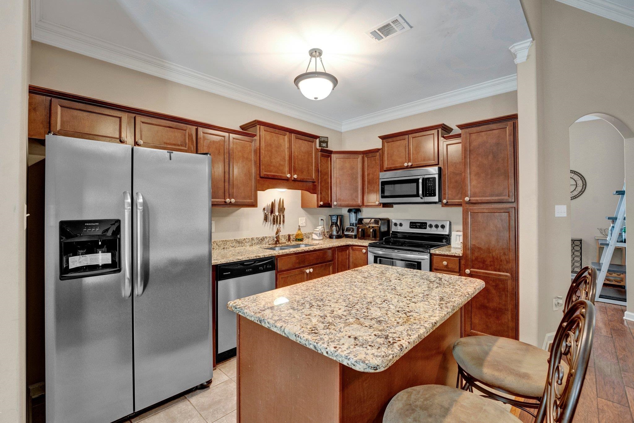 Kitchen featuring ornamental molding, a center island, light hardwood / wood-style flooring, and stainless steel appliances