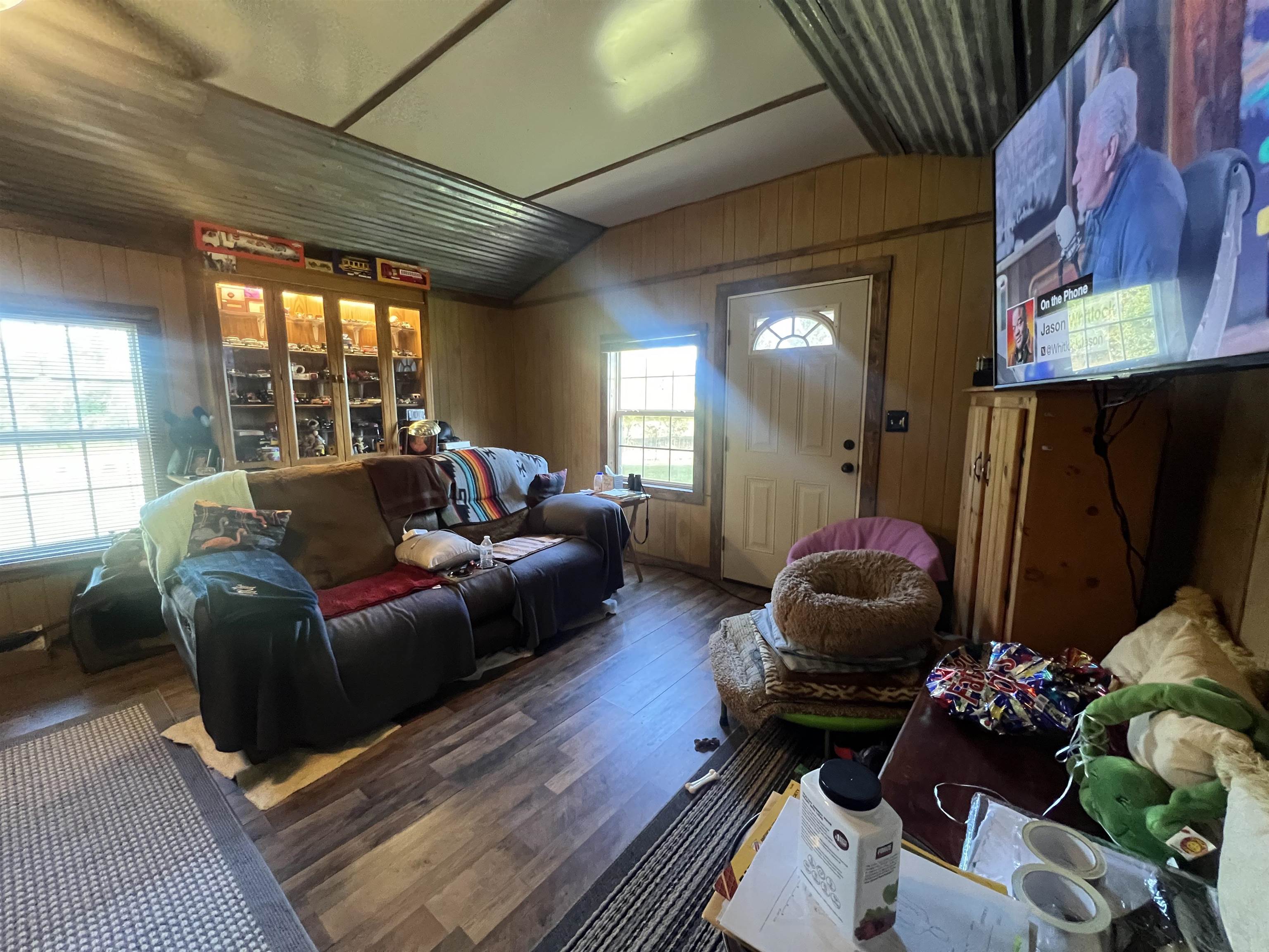 Living room with vaulted ceiling, wood walls, and dark hardwood / wood-style flooring