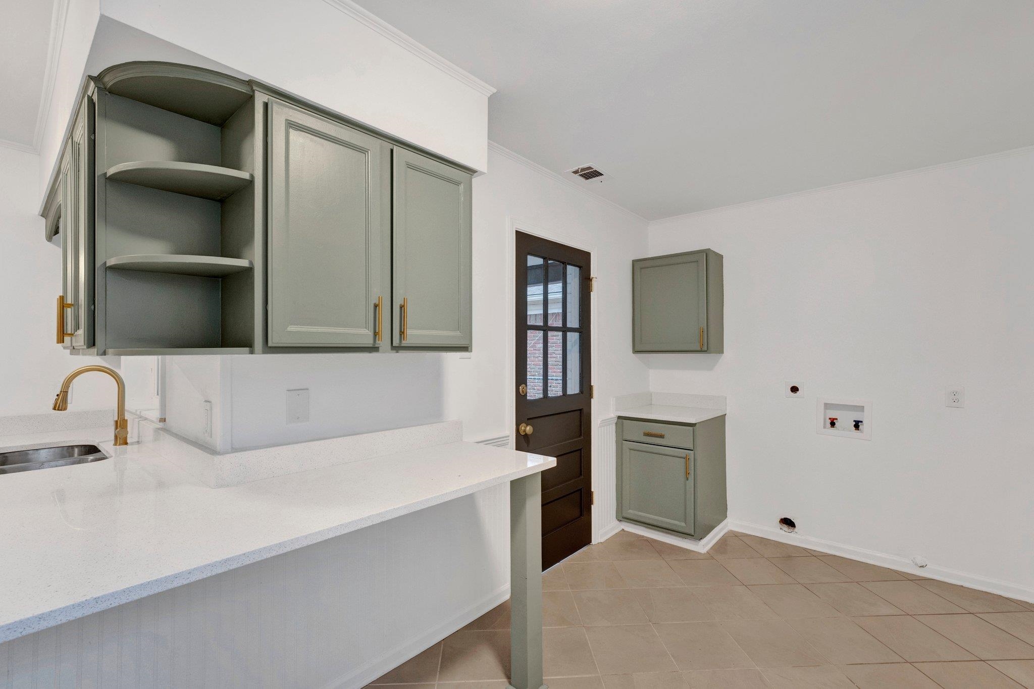 Kitchen with light tile patterned floors, light stone counters, and sink