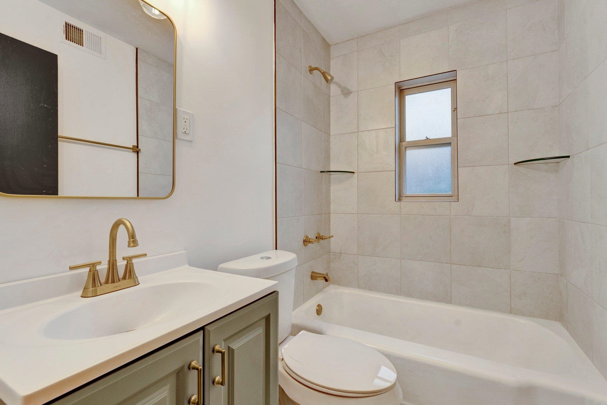 Full bathroom with toilet, tiled shower / bath combo, and vanity