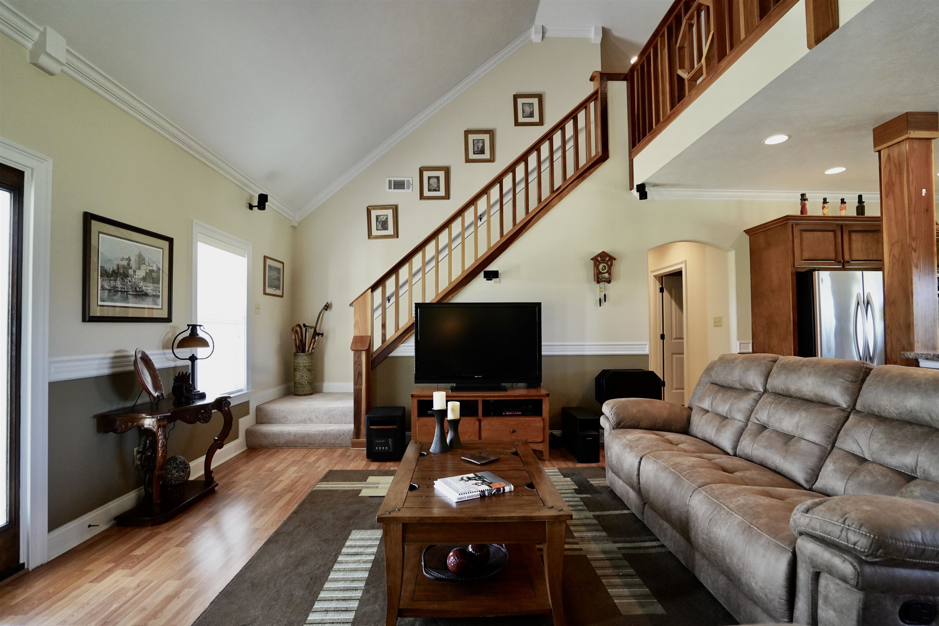 Living room with high vaulted ceiling, light hardwood / wood-style floors, and crown molding