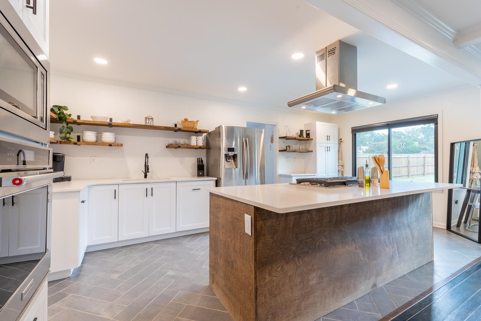 Kitchen featuring a kitchen island, appliances with stainless steel finishes, island exhaust hood, ornamental molding, and sink