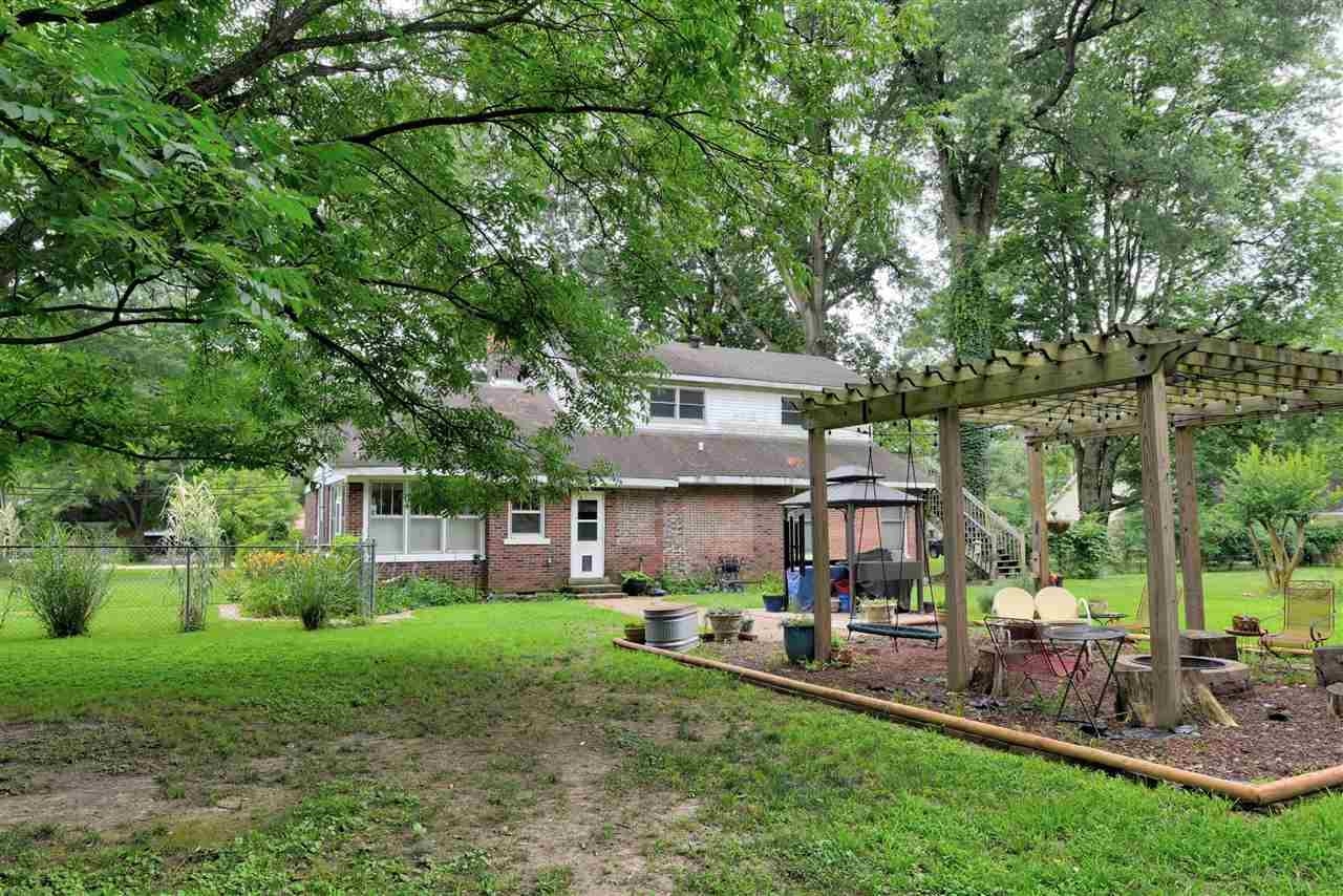 Back of house featuring a pergola and a lawn