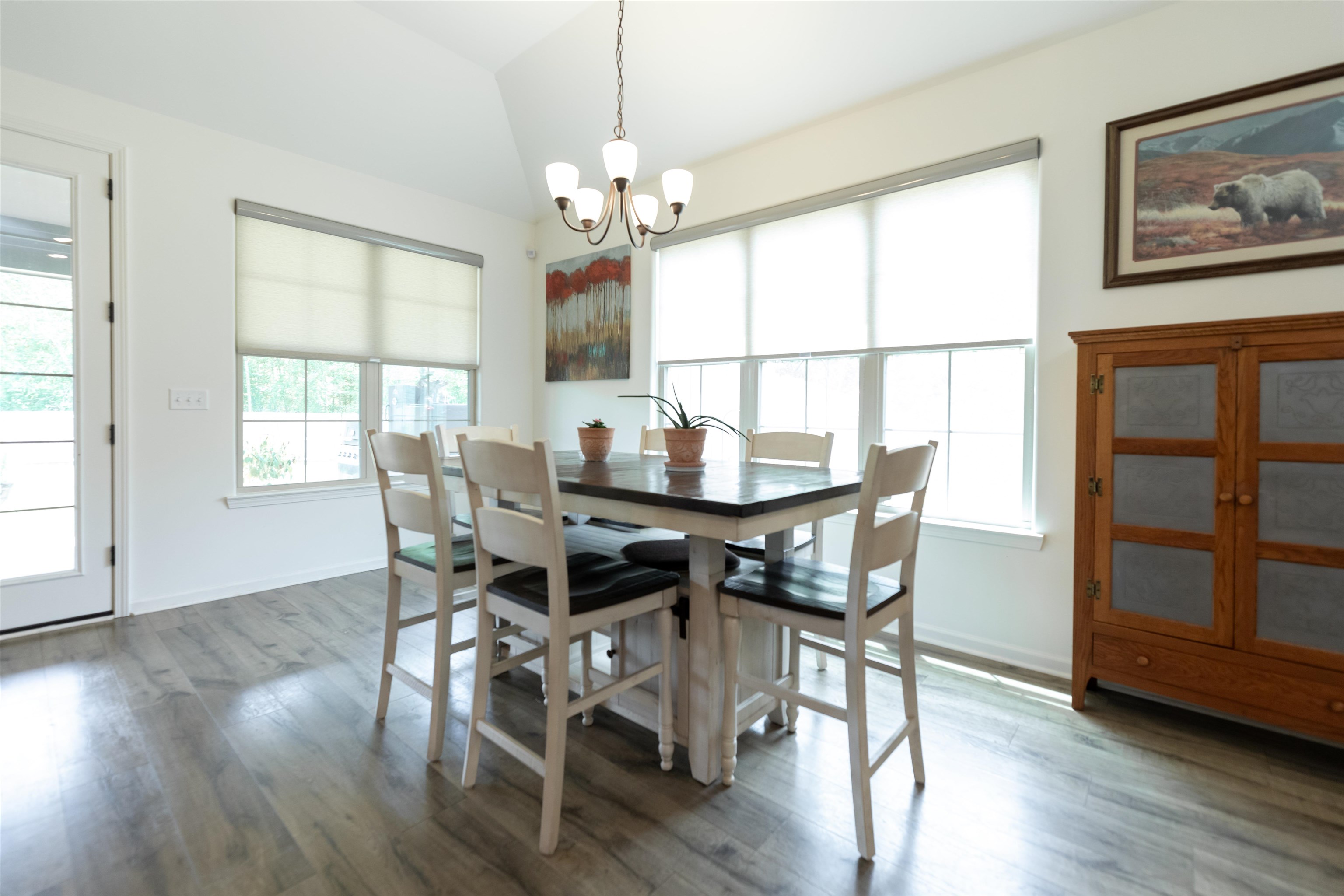 Dining area with vaulted ceiling, hardwood / wood-style flooring, and an inviting chandelier