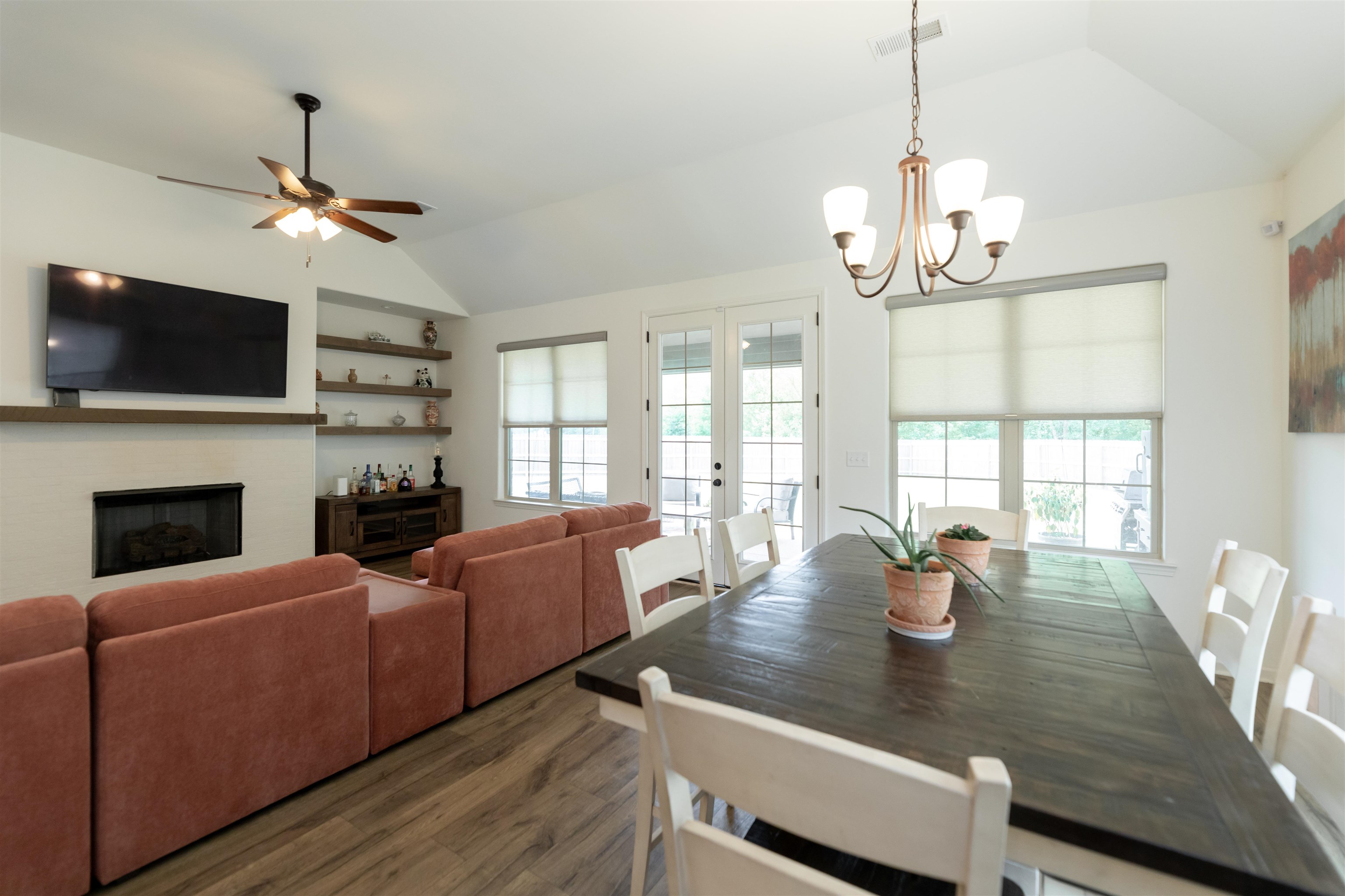 Dining room featuring ceiling fan with notable chandelier, dark wood-type flooring, lofted ceiling, and french doors