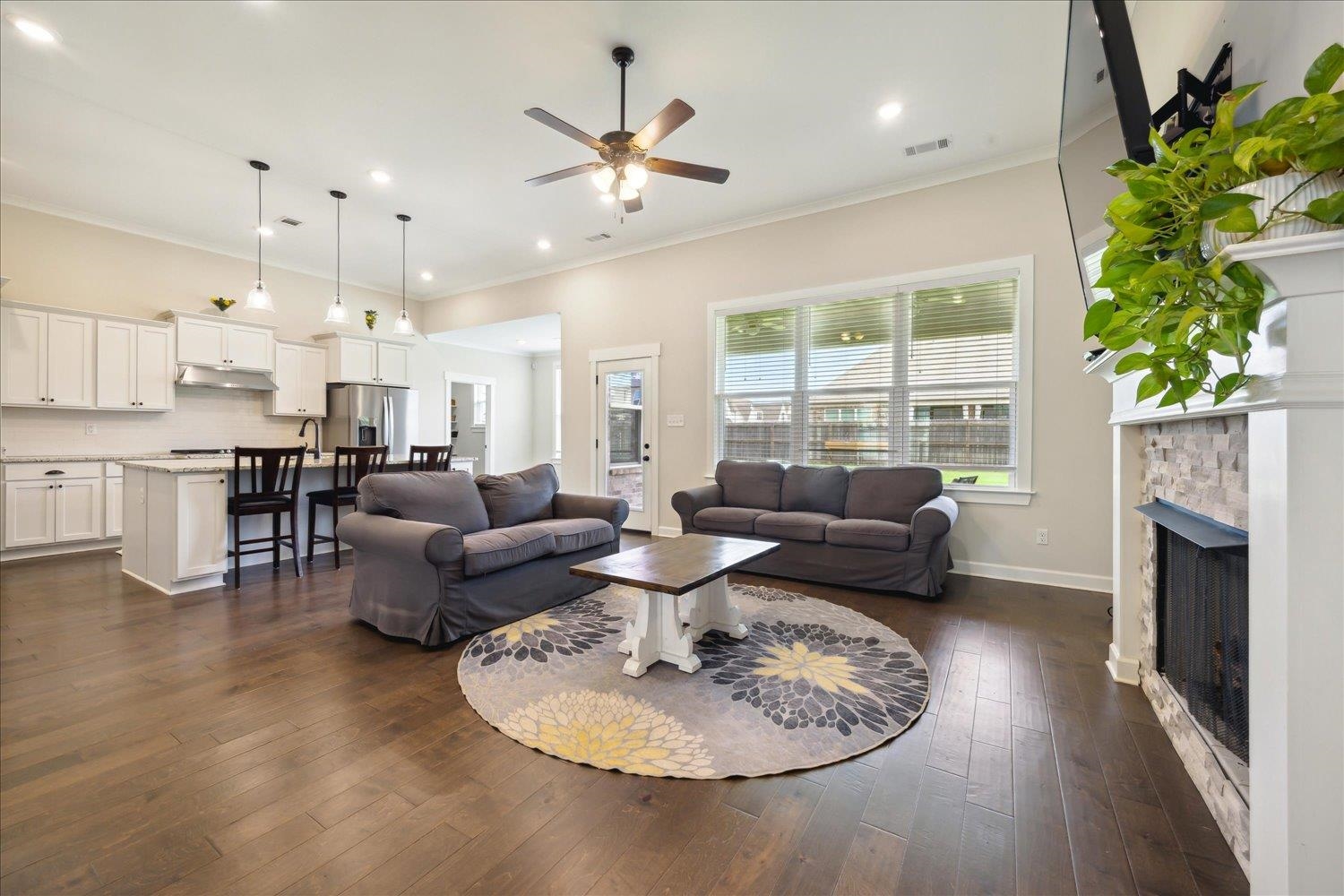 Living room featuring crown molding, ceiling fan, dark hardwood / wood-style flooring, and a fireplace